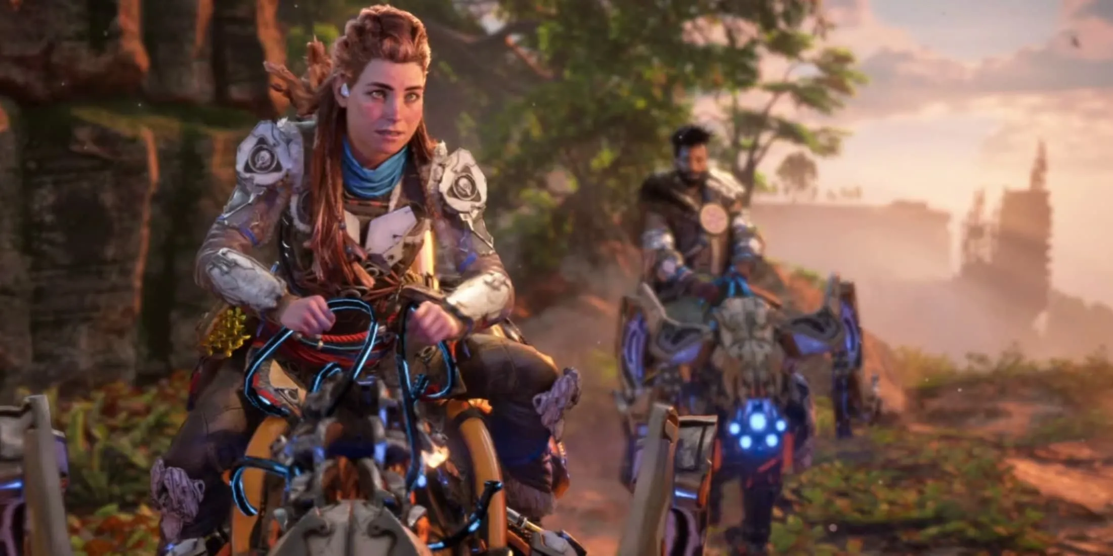 Aloy, nhân vật chính từ Horizon Forbidden West, đang cưỡi một cỗ máy trong một phân cảnh điện ảnh, với một nhân vật khác ở phía sau.