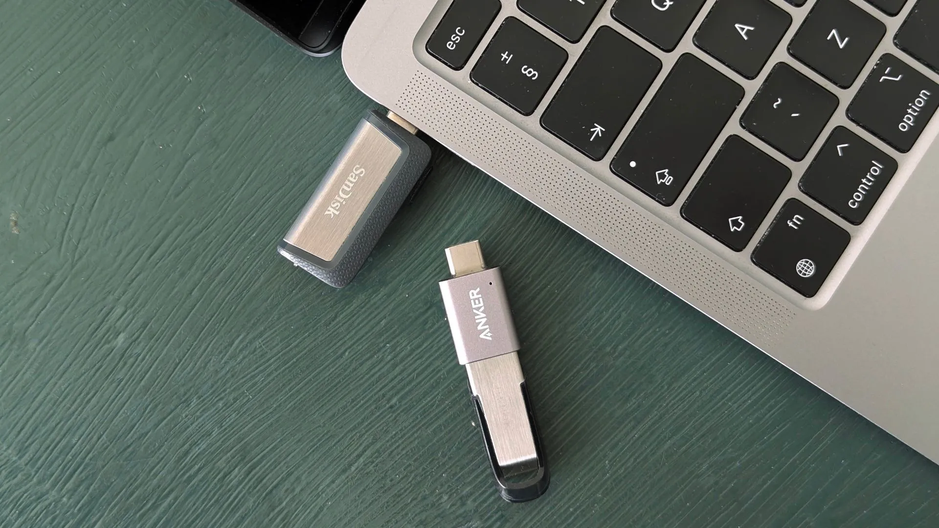 Các mẫu USB flash drive hiện đại được đặt cạnh một chiếc MacBook, minh họa sự đa dạng về cổng kết nối USB (USB-A, USB-C) và thiết kế nhỏ gọn của các thiết bị lưu trữ di động.