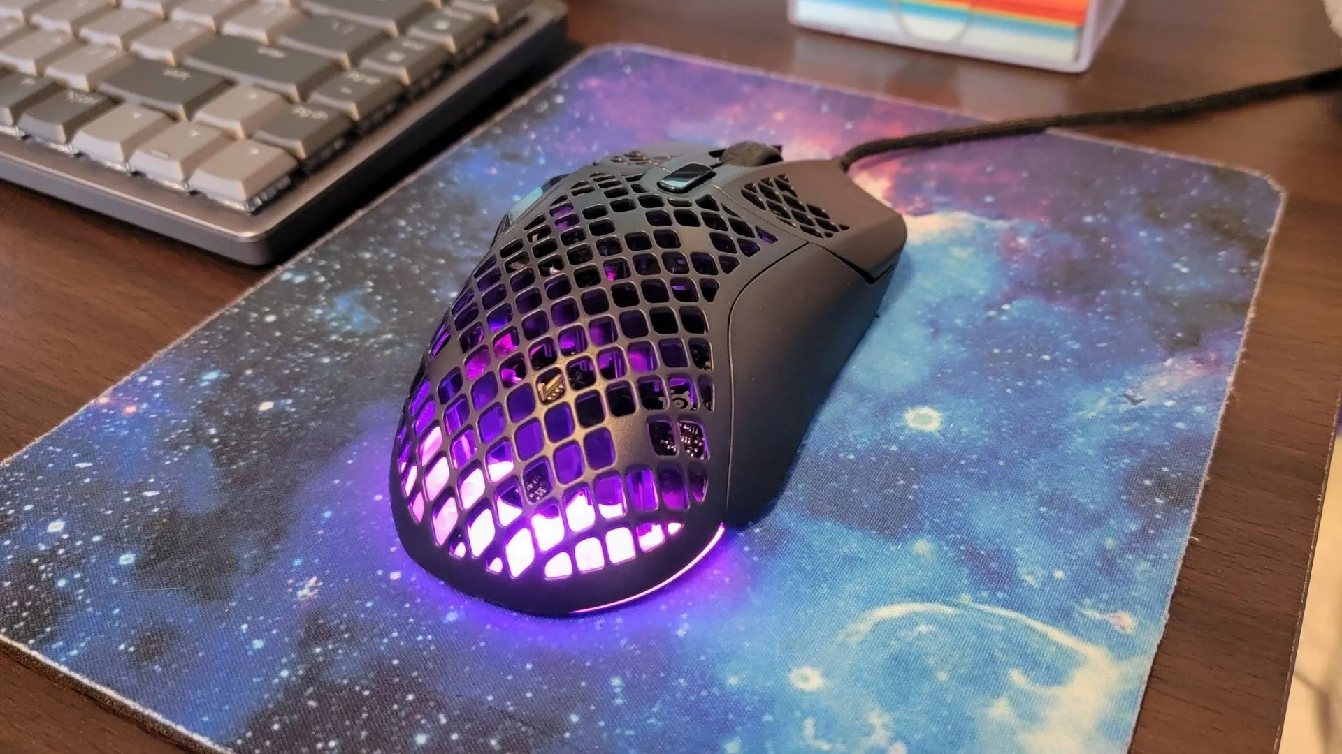 Cận cảnh chuột gaming SteelSeries Aerox 5 Wired trên tấm lót chuột họa tiết thiên hà, nổi bật thiết kế nhẹ và hiệu suất cao.