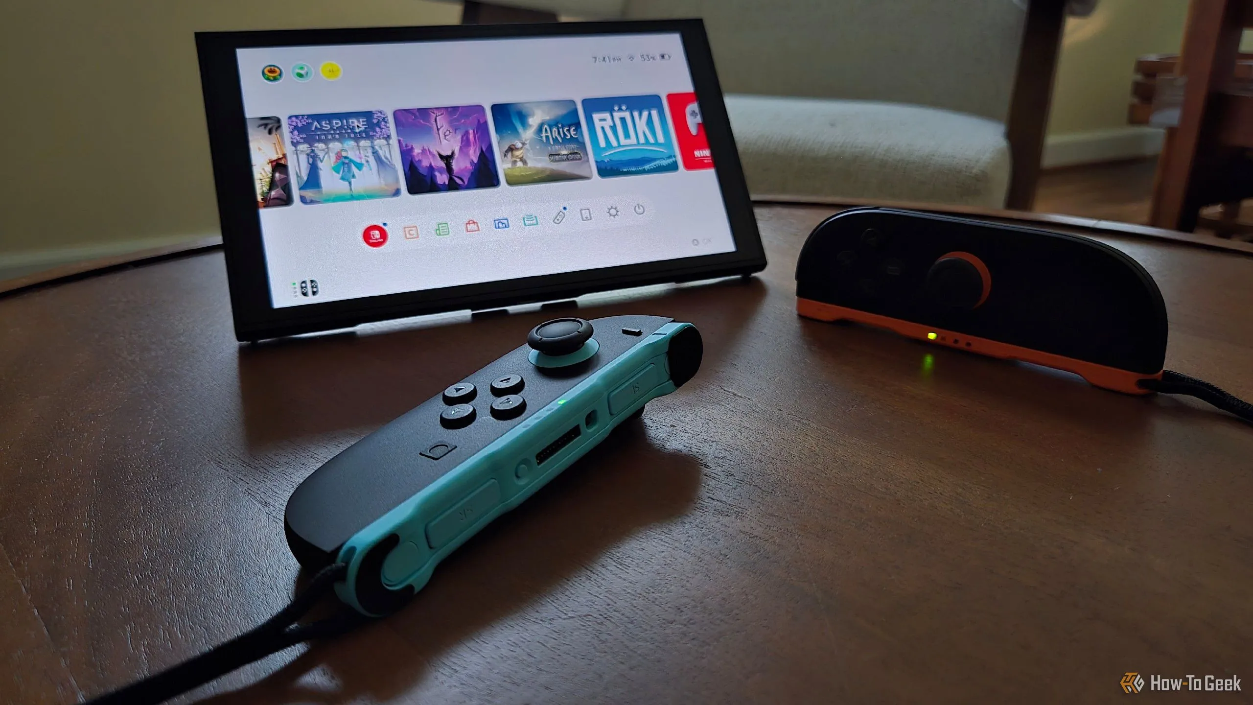 Cặp tay cầm Joy-Con 2 đặt phía trước máy Switch 2 đang dựng đứng bằng chân đế tích hợp, một tay cầm được dùng như chuột.