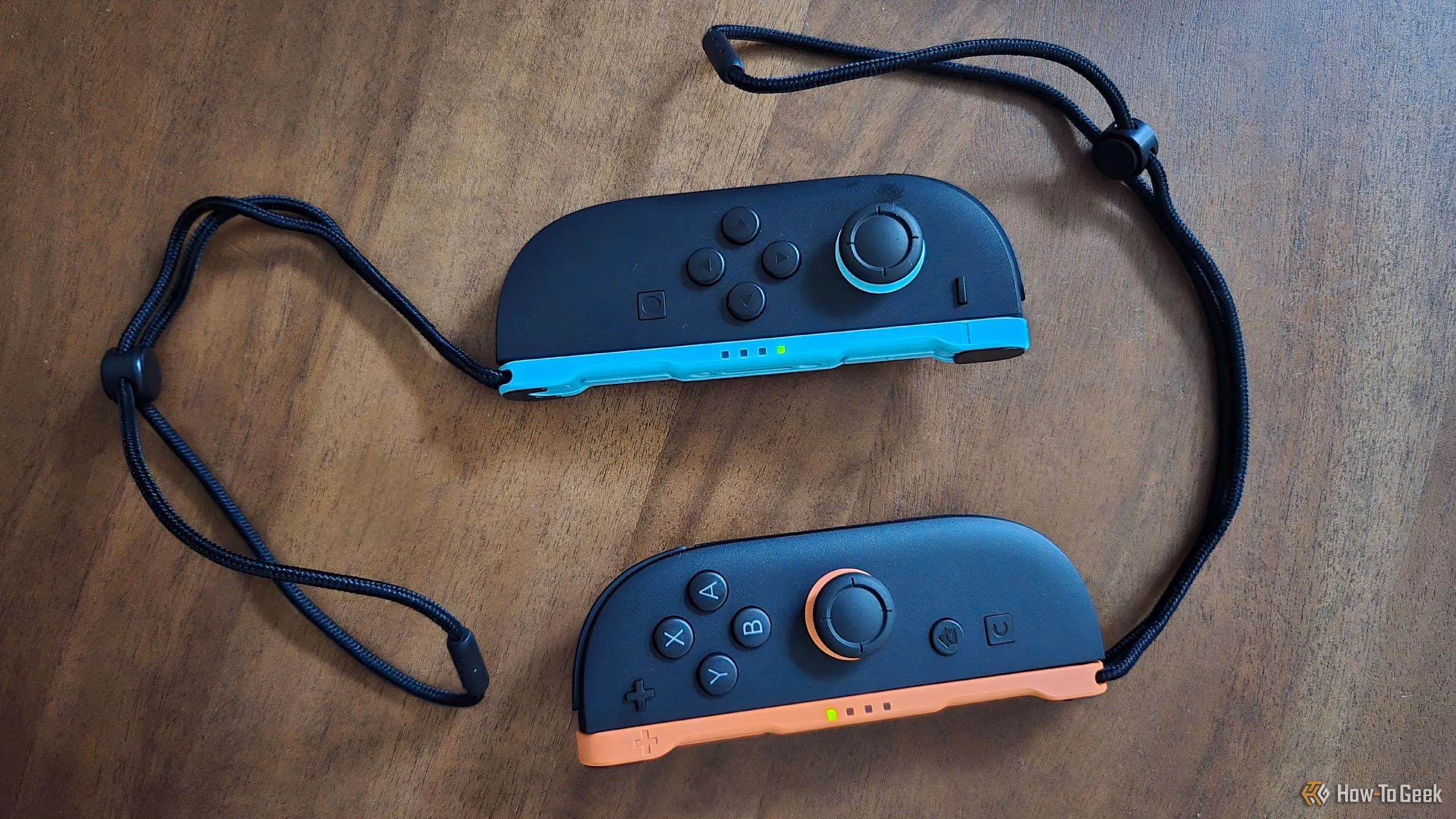 Cặp tay cầm Joy-Con 2 đặt trên bàn, kèm theo dây đeo cổ tay.