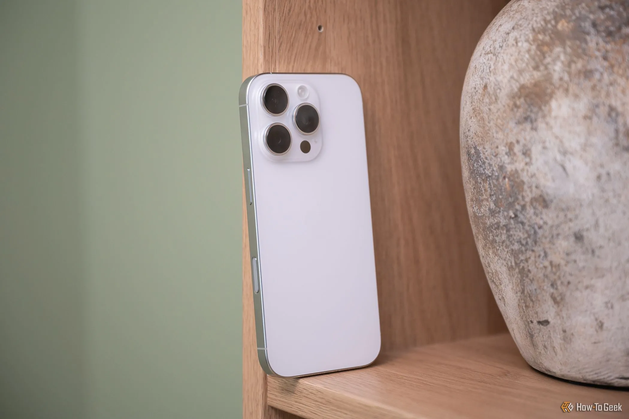 Điện thoại iPhone 16 Pro đặt trên giá sách, làm nổi bật nút điều khiển camera mới.