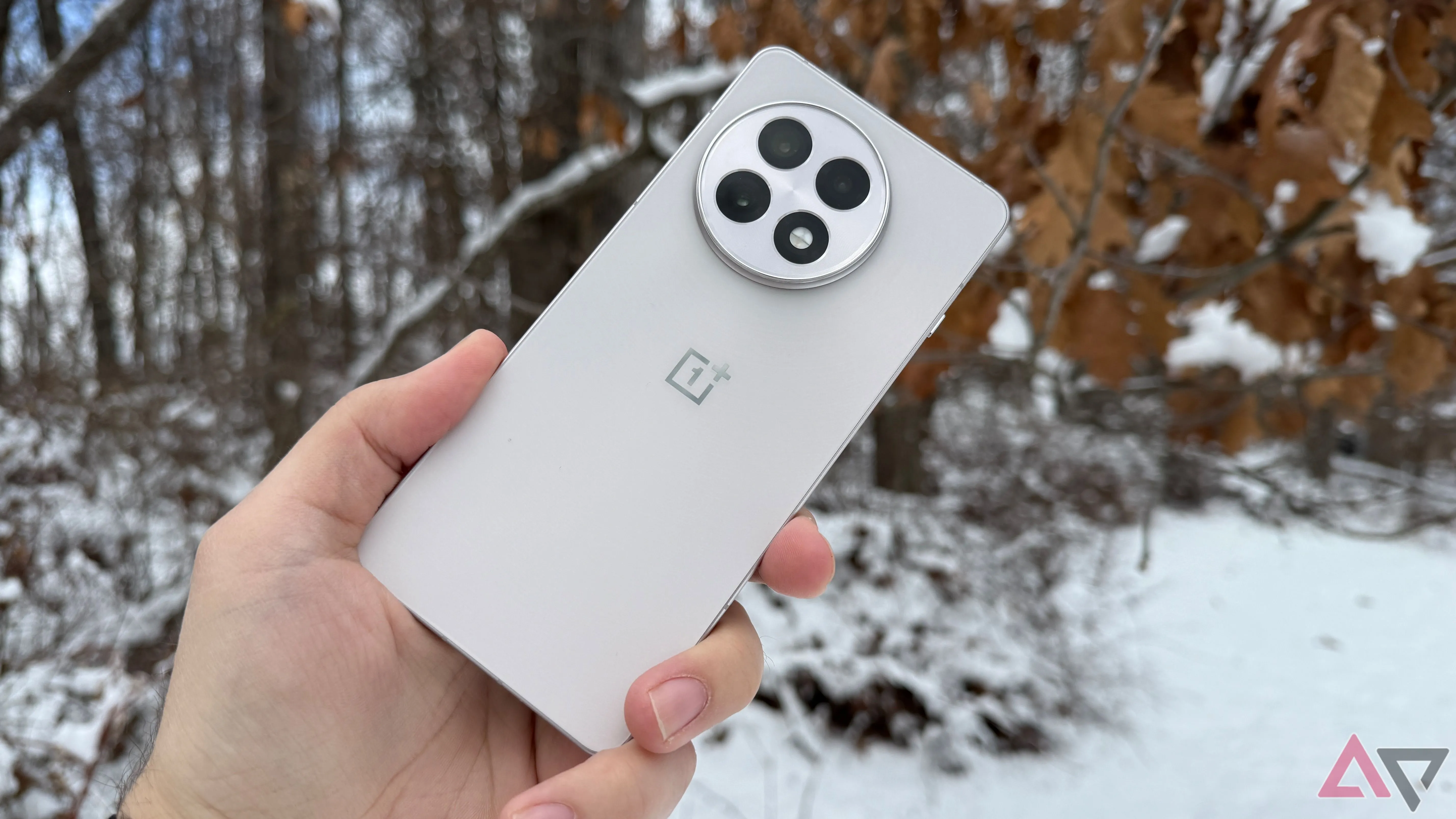 Điện thoại OnePlus 13R màu đen được cầm trên tay giữa khung cảnh tuyết trắng, tôn lên thiết kế sang trọng