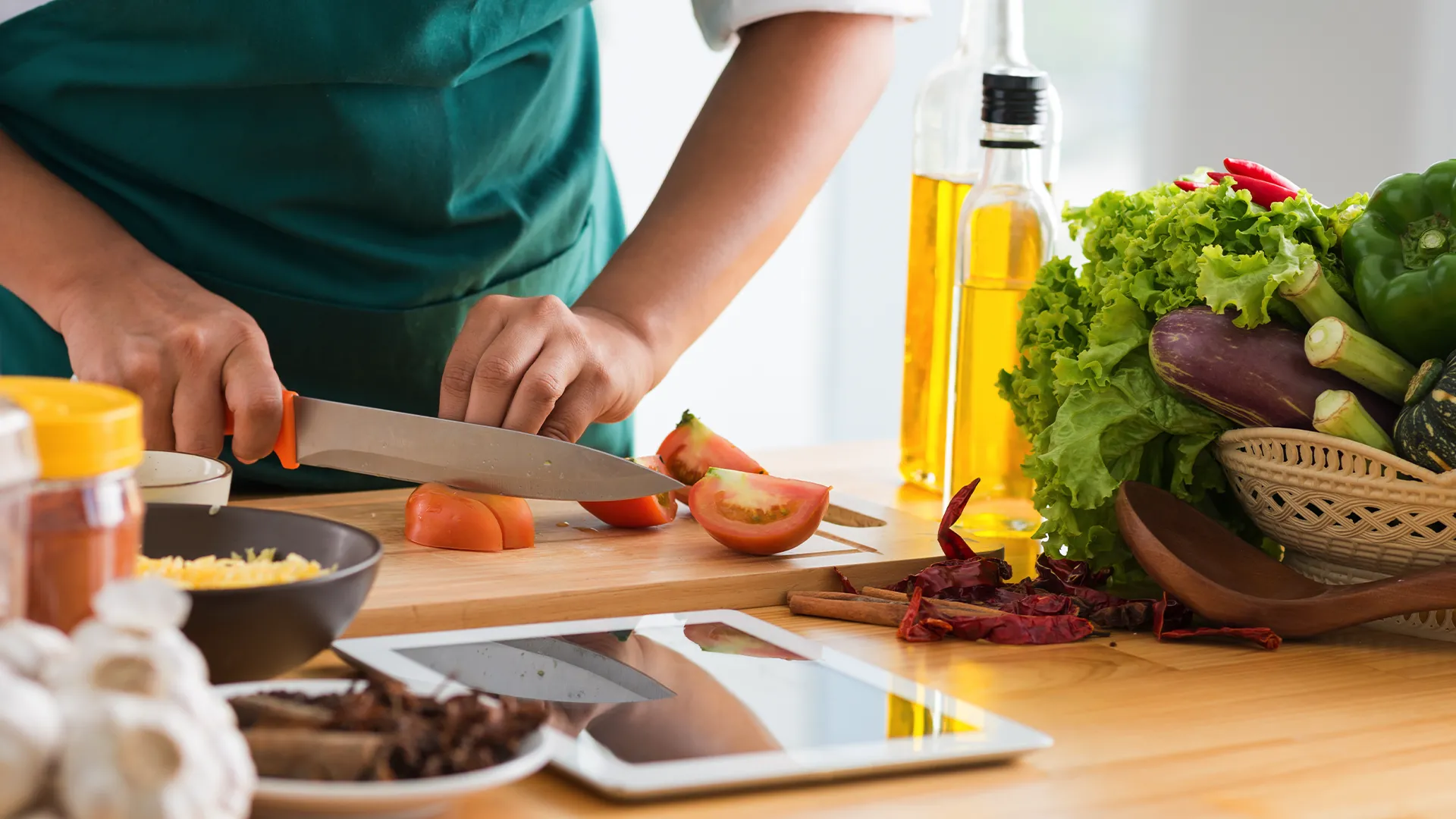 Gần gũi cảnh nấu ăn với người phụ nữ đang cắt rau, minh họa việc sử dụng thiết bị điện tử trong bếp