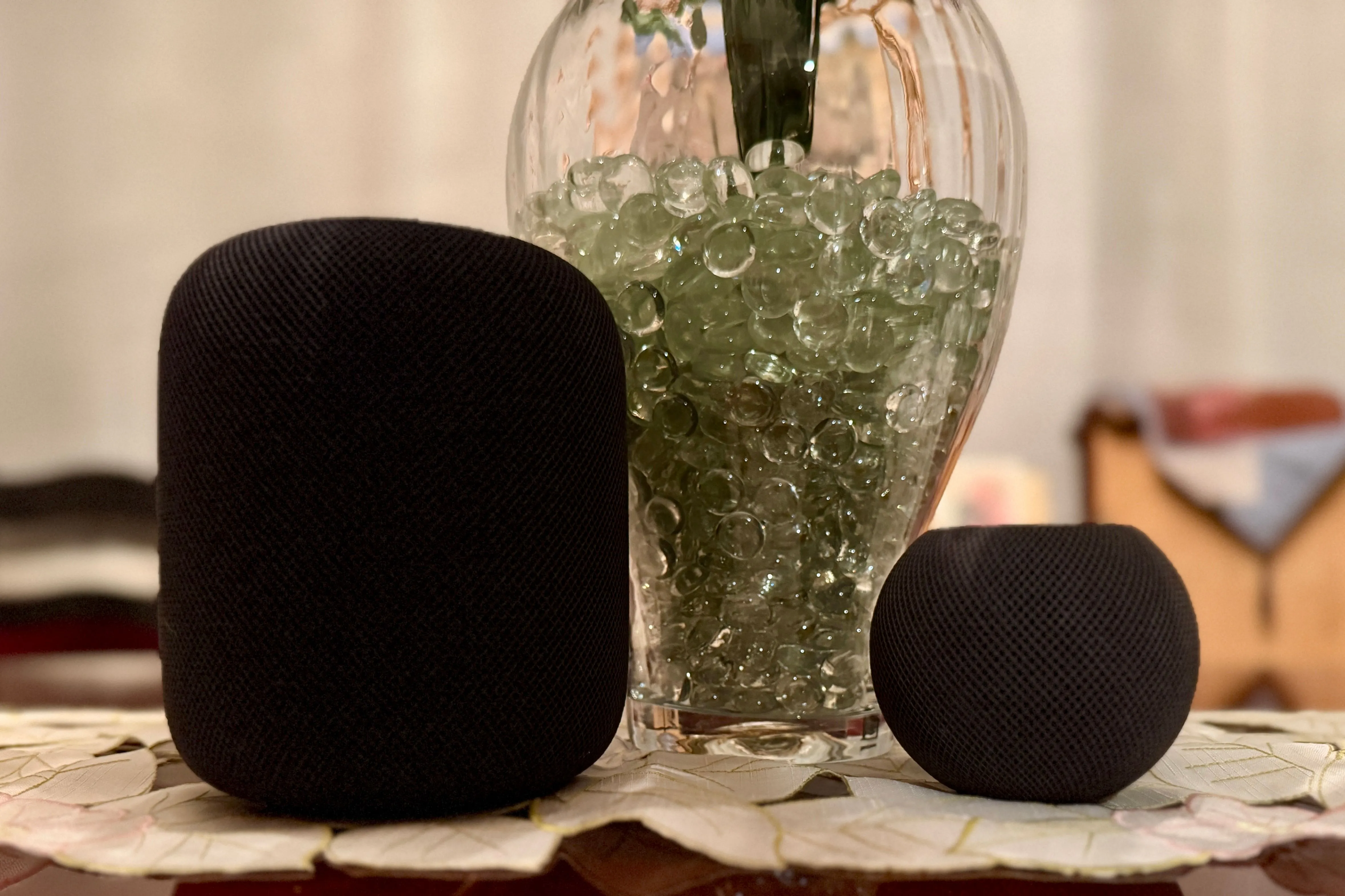 Hai chiếc HomePod màu đen cạnh một chiếc bình chứa hạt cườm