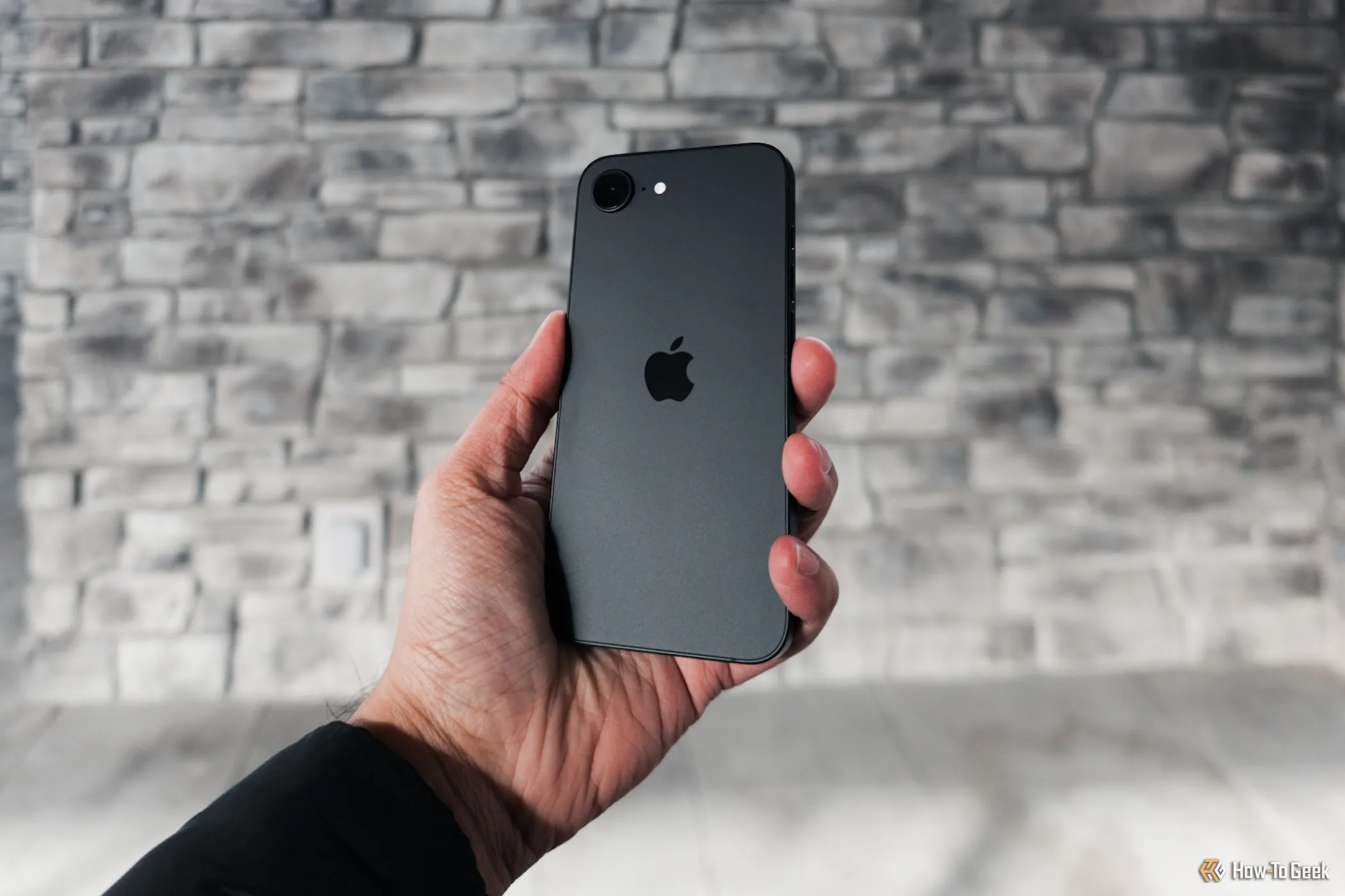 iPhone 16e được cầm nghiêng trên tay, làm nổi bật đường cong nhẹ ở các cạnh viền