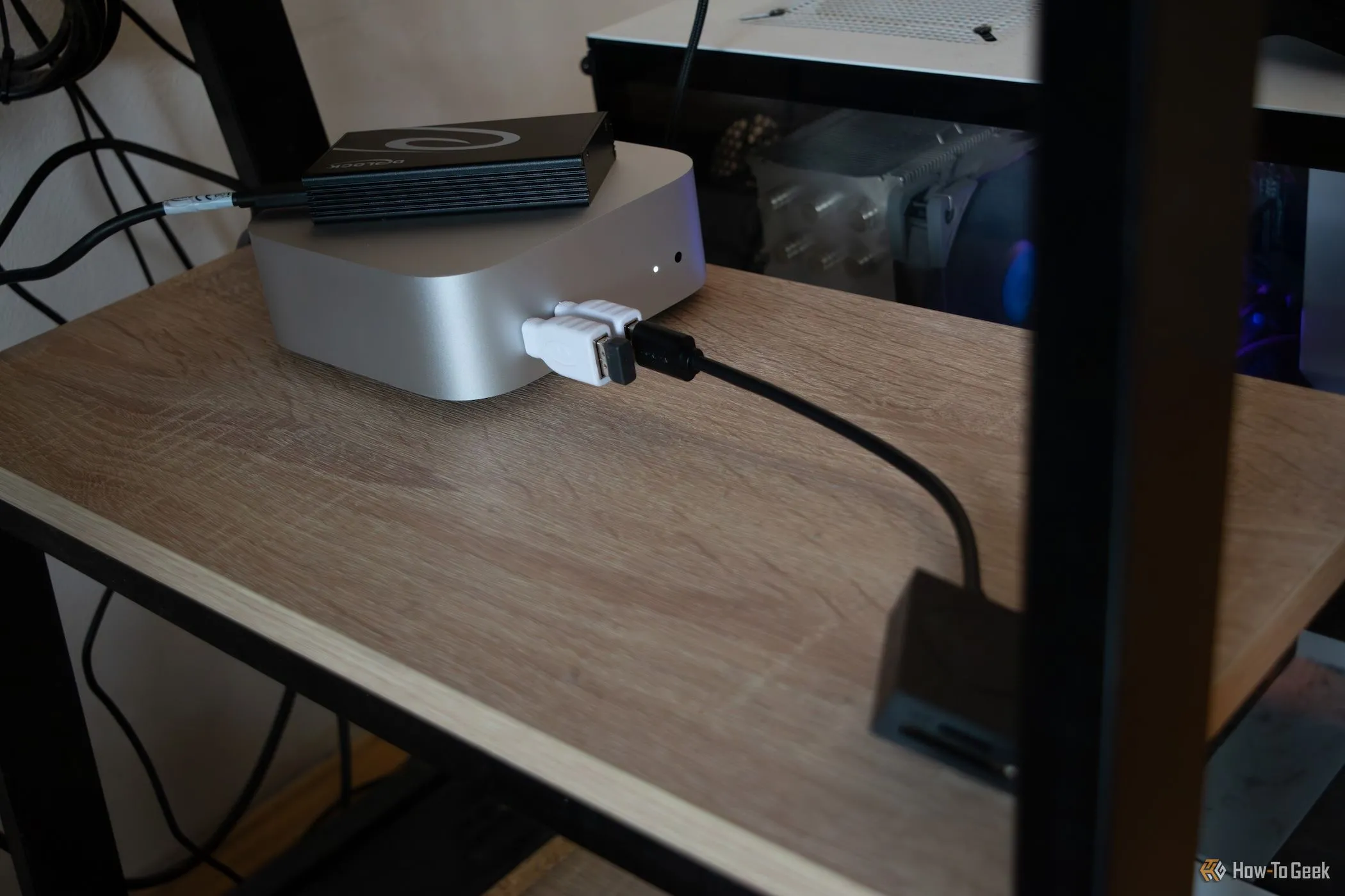 Mac Mini M4 đặt dưới bàn làm việc, kết nối với ổ cứng SSD gắn ngoài.