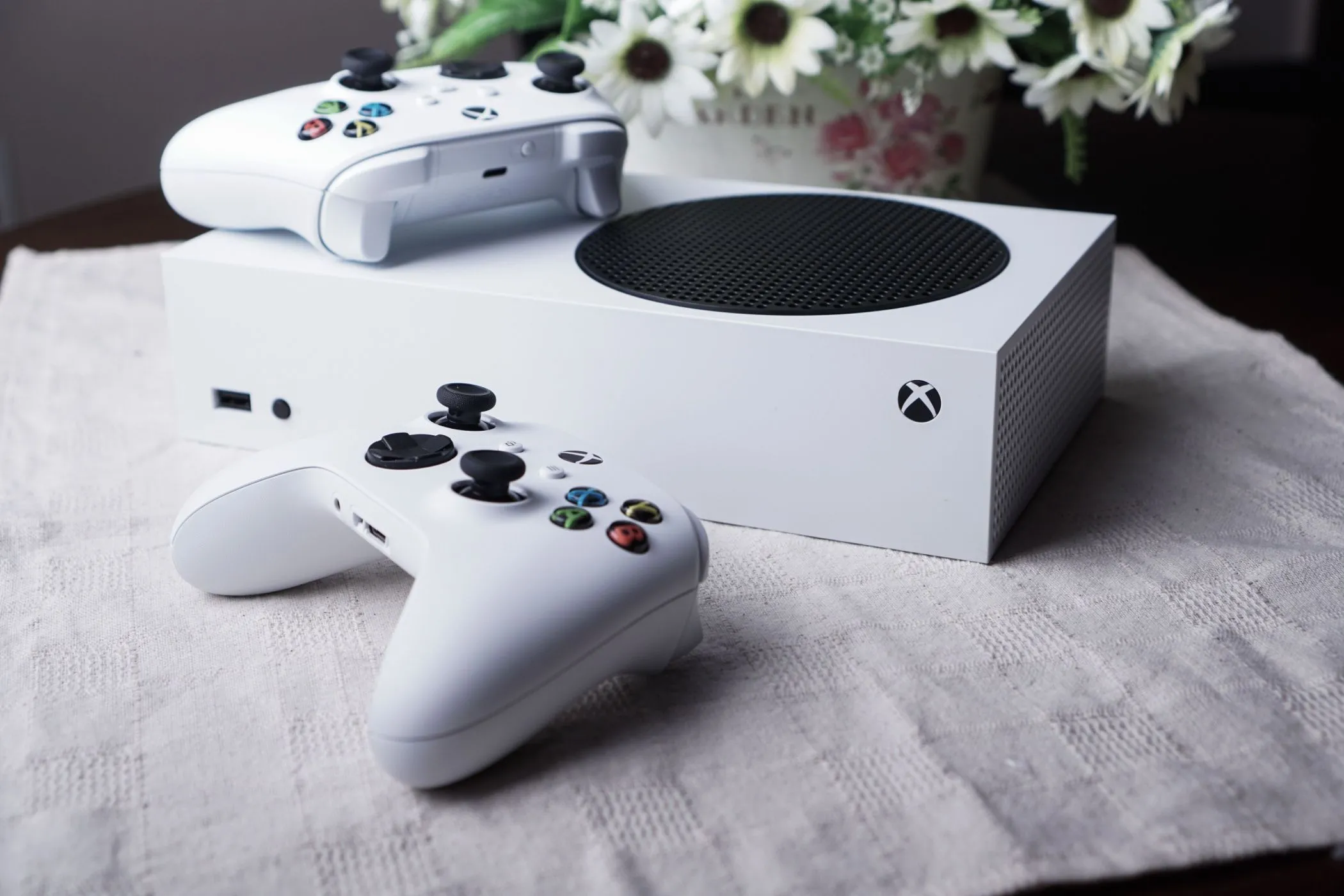 Máy chơi game Xbox Series S màu trắng cùng hai tay cầm trên bàn, biểu trưng cho tiềm năng tối ưu game.