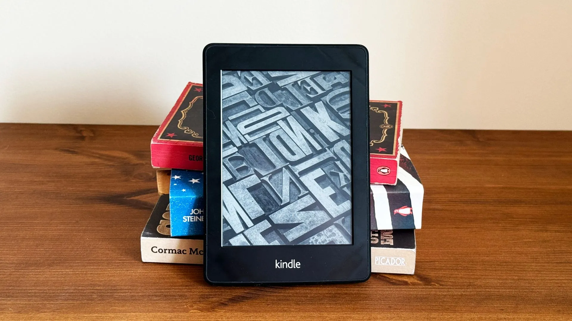 Máy đọc sách Kindle đặt trước chồng sách giấy