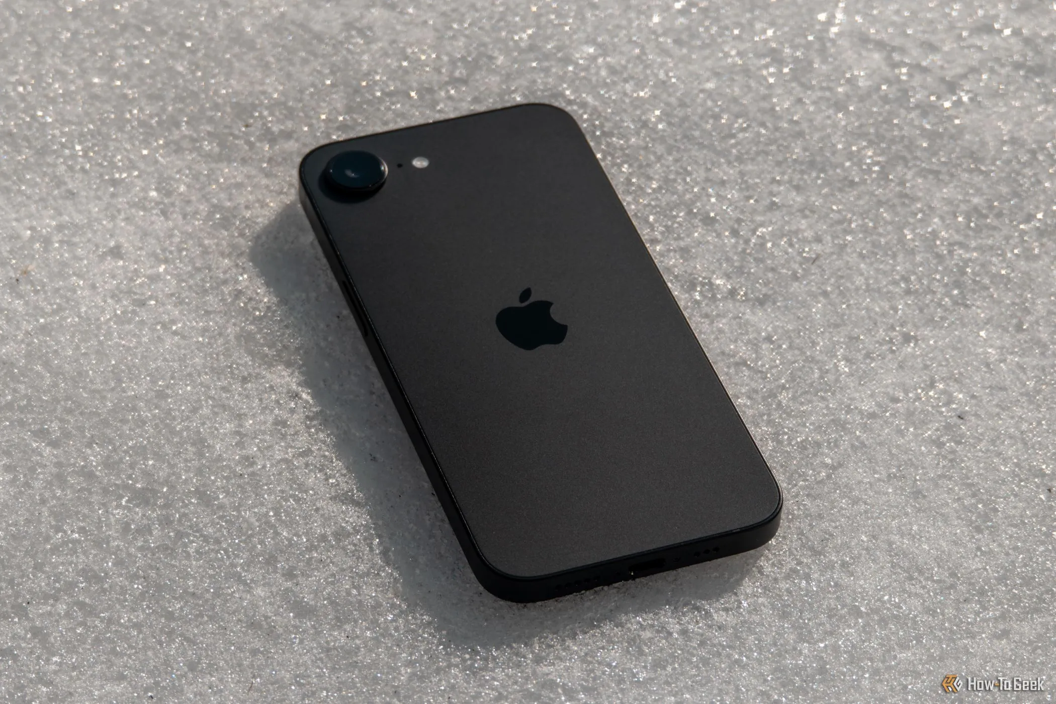 Một chiếc iPhone 16e đặt úp trên tuyết, tượng trưng cho vai trò của thiết bị công nghệ cá nhân trong việc hỗ trợ lối sống năng động và khỏe mạnh.