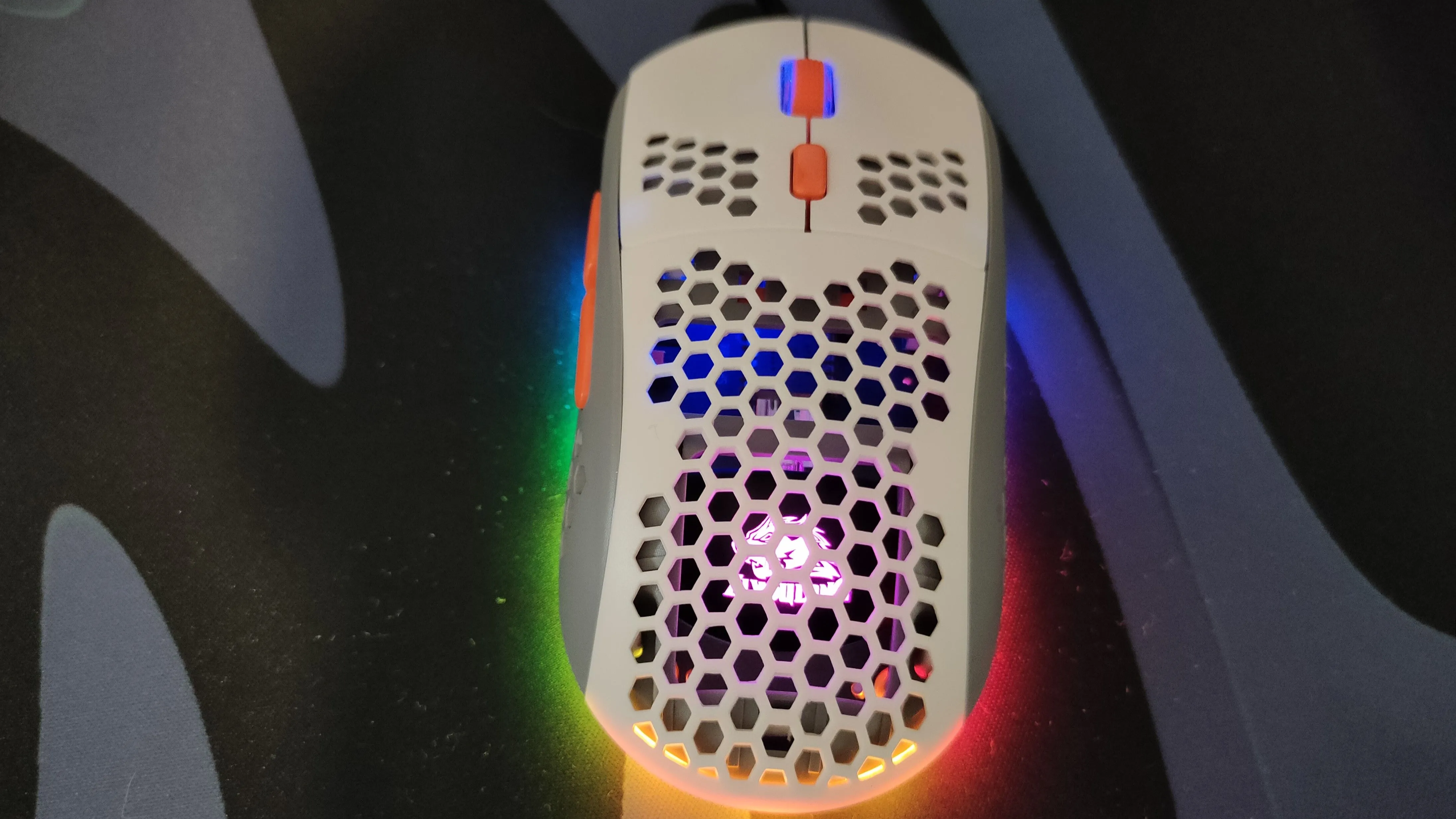 Một con chuột gaming màu trắng có lỗ và đèn RGB.