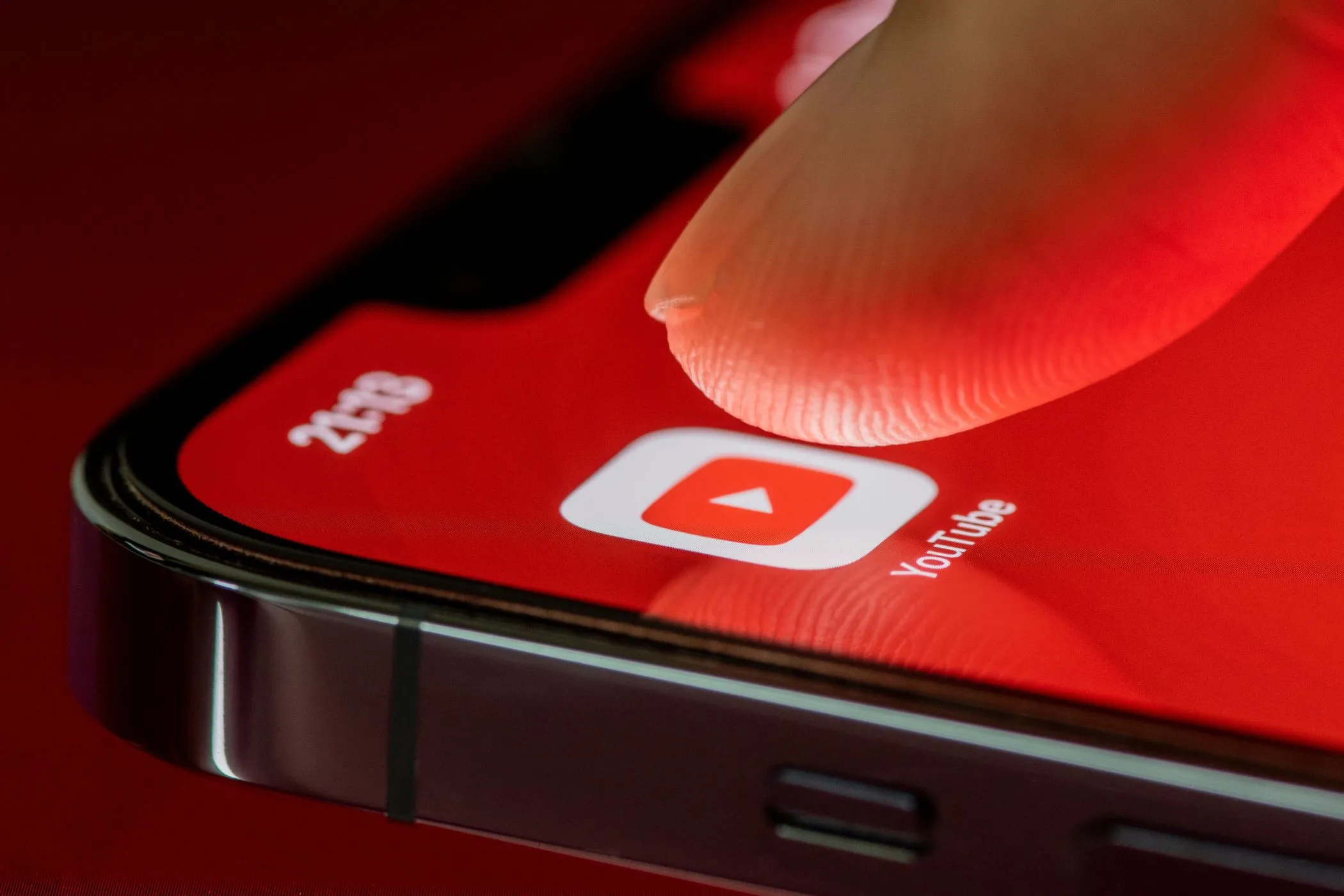 Một ngón tay đang chạm vào biểu tượng ứng dụng YouTube trên màn hình điện thoại iPhone, thể hiện việc truy cập ứng dụng để không ảnh hưởng đến gợi ý cá nhân khi dùng chế độ ẩn danh.