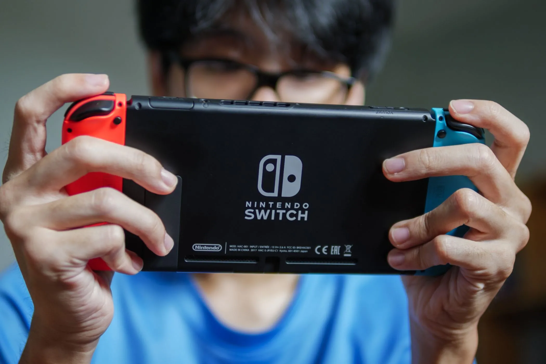 Người đàn ông chơi game trên máy console Nintendo Switch ở chế độ cầm tay