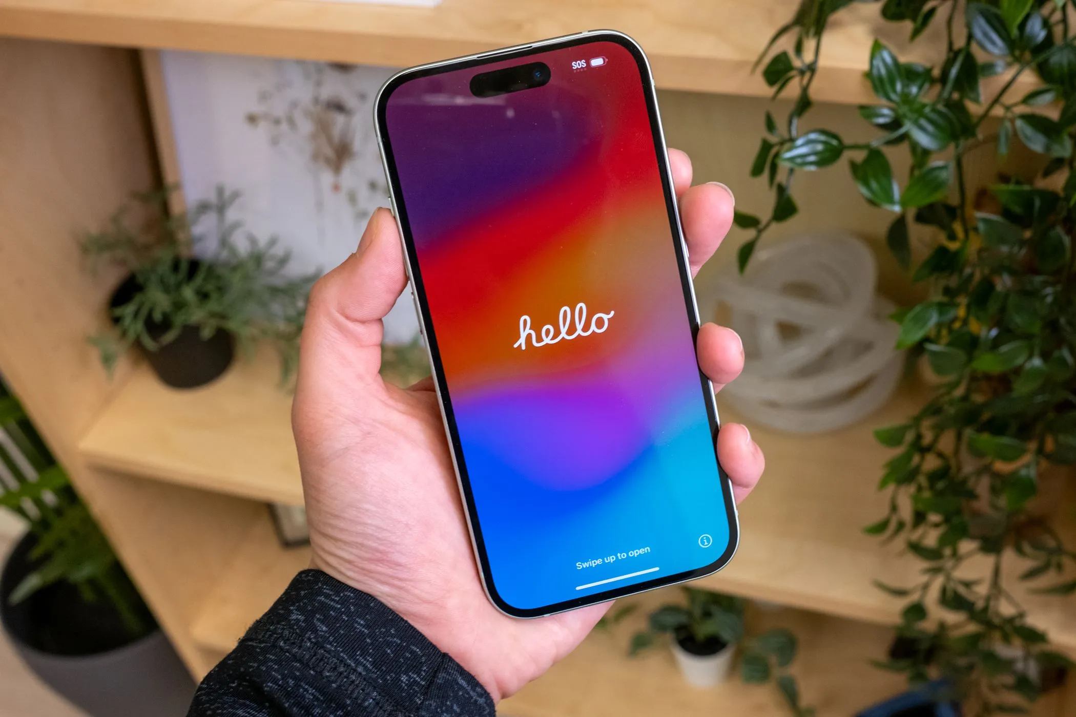 Người đang cầm chiếc iPhone 15 màu xanh lá cây với màn hình chào mừng
