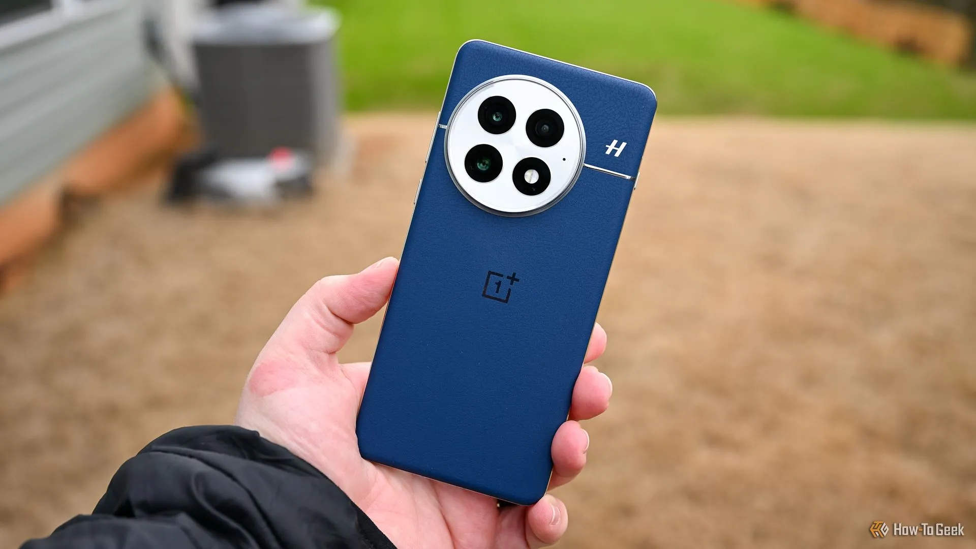 Người dùng cầm điện thoại OnePlus 13 màu xanh dương, khoe mặt lưng và cụm camera, minh họa thiết kế hiện đại của sản phẩm