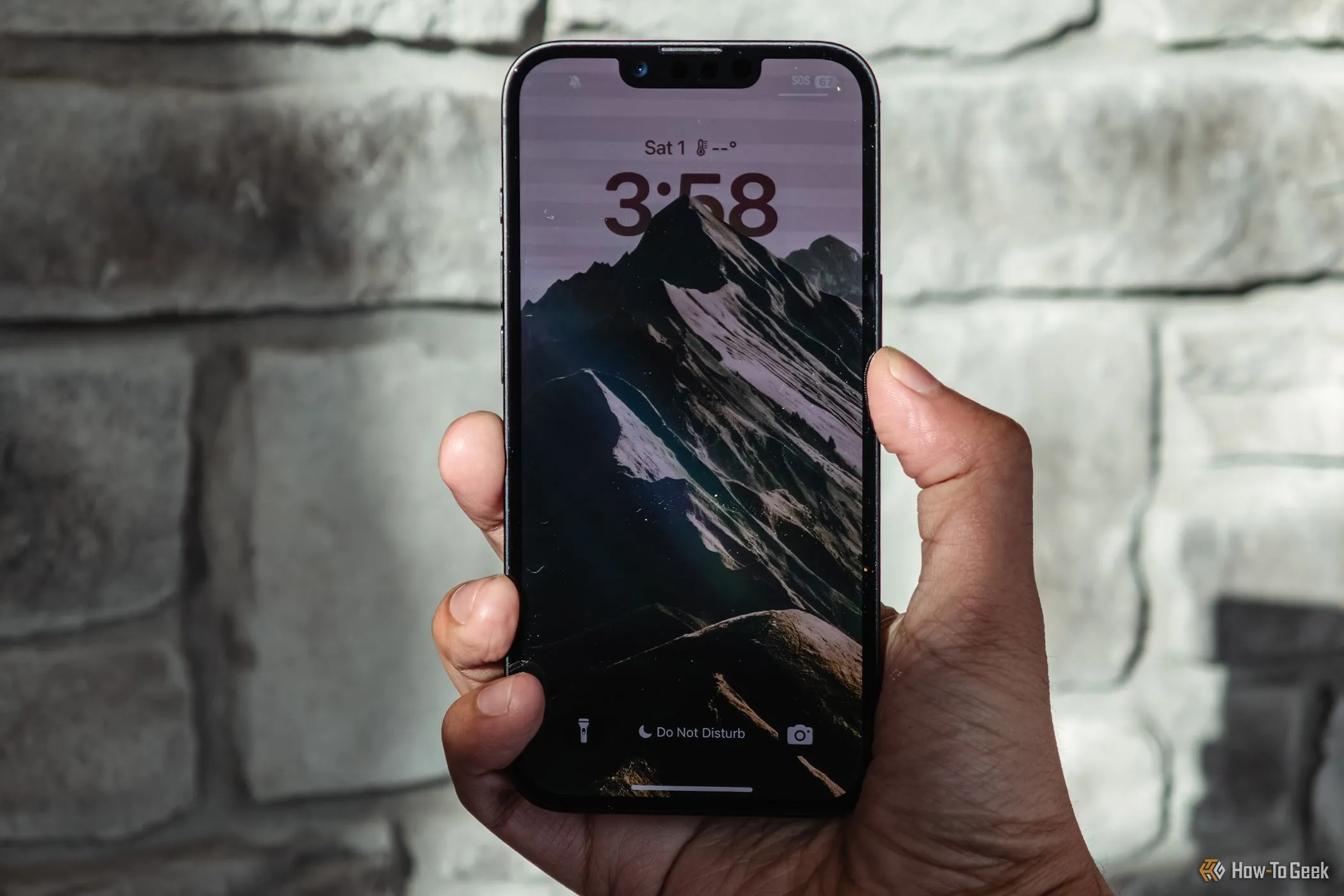 Người dùng cầm iPhone 16e trên tay với màn hình khóa đang hiển thị, làm rõ phần &quot;tai thỏ&quot;