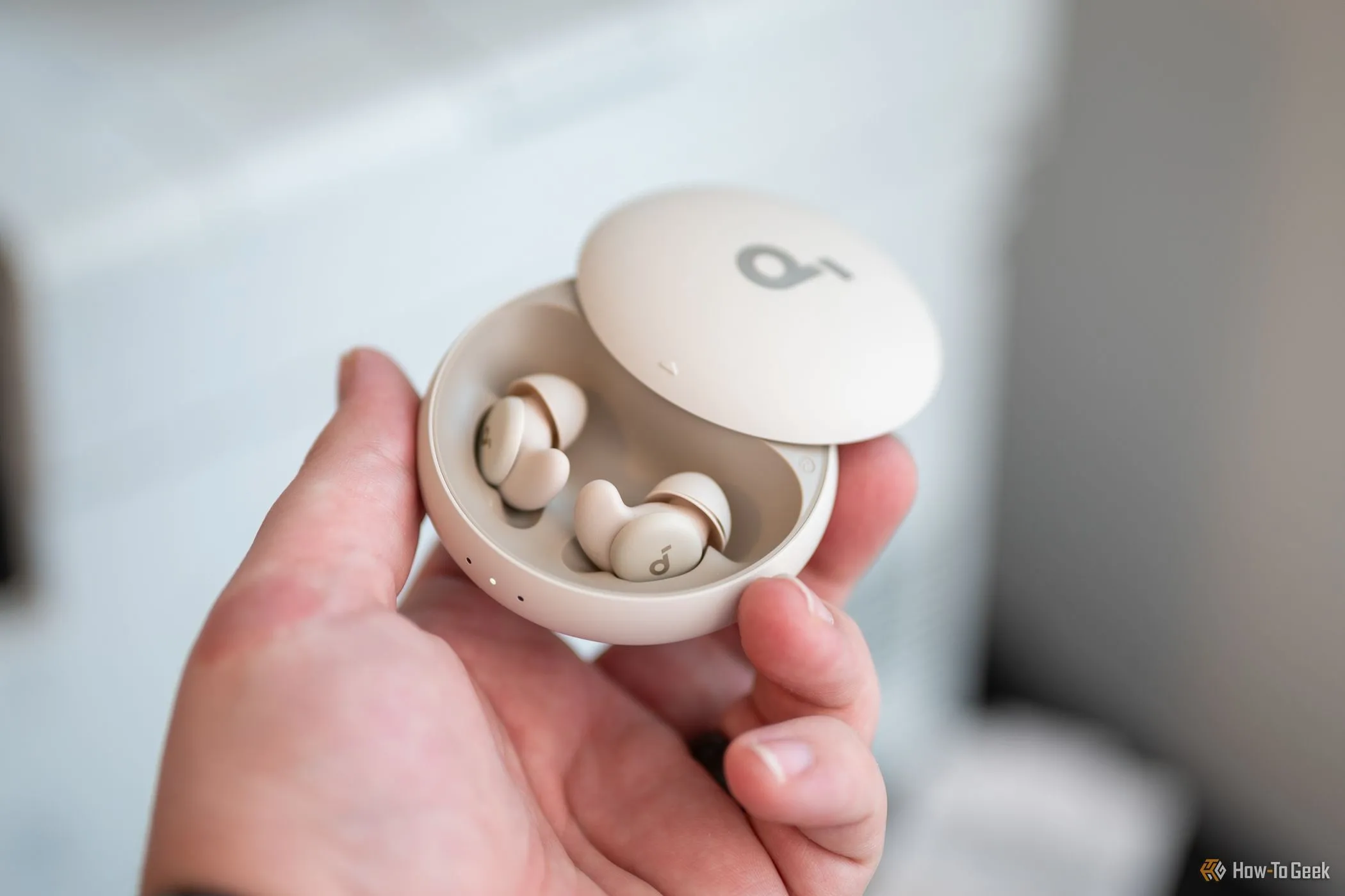 Người dùng cầm tai nghe Soundcore Sleep A20 bên trong hộp sạc, thể hiện trạng thái sạc liên tục khi không sử dụng.