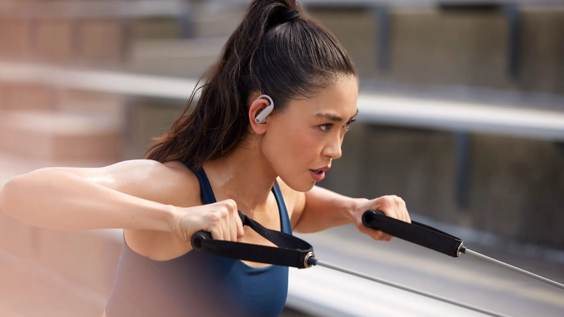 Tai nghe Powerbeats Pro 2 màu đen đang được đeo trên tai của người phụ nữ đang tập thể dục