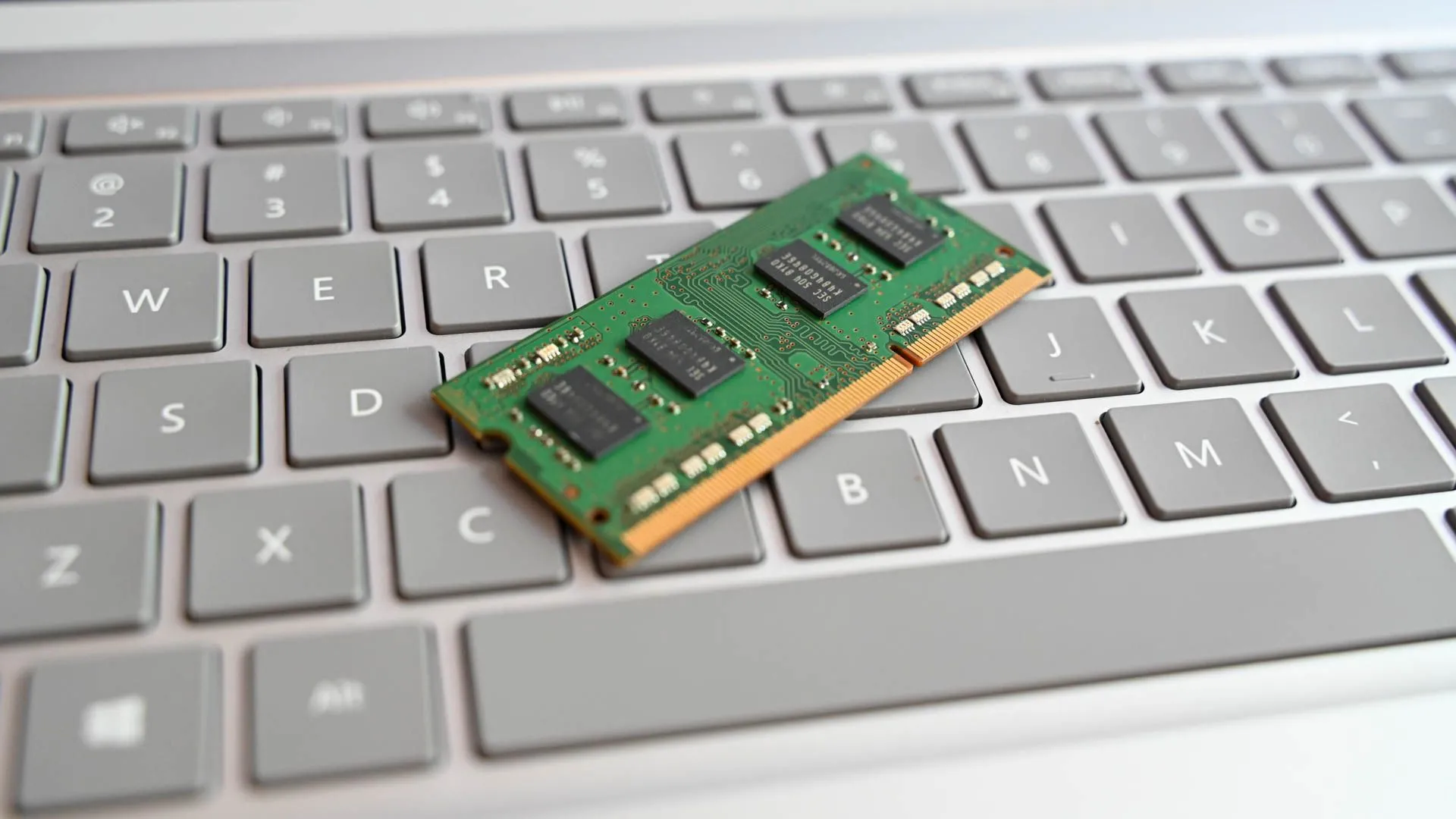 Thanh RAM laptop đặt trên bàn phím của một chiếc laptop, tượng trưng cho tầm quan trọng của RAM trong việc đảm bảo hiệu suất mượt mà cho các hệ thống máy tính và NAS.