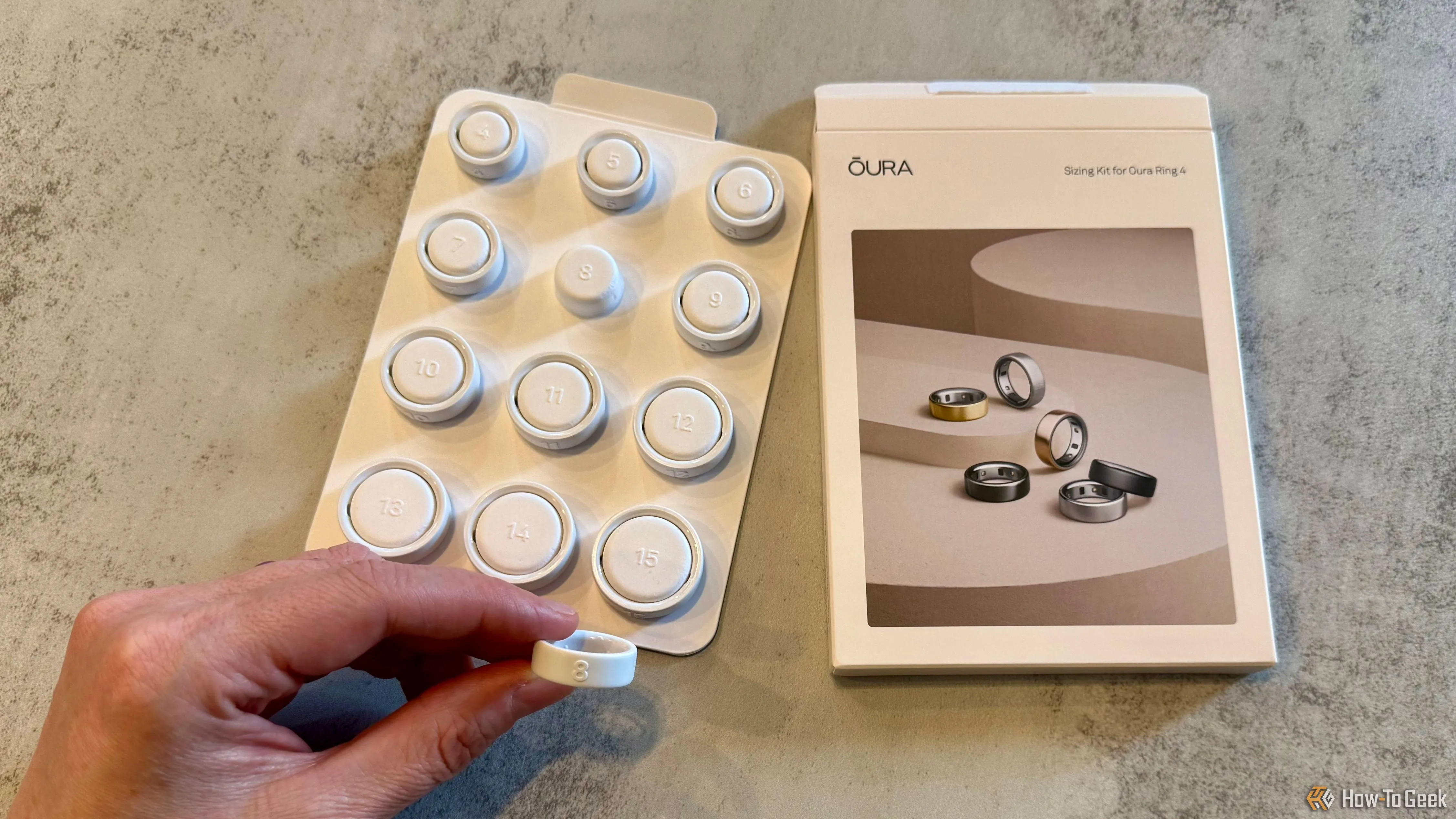 Bộ kit thử kích cỡ Oura Ring 4 với một chiếc nhẫn thử màu đen được cầm trên tay, giúp người dùng chọn size phù hợp nhất