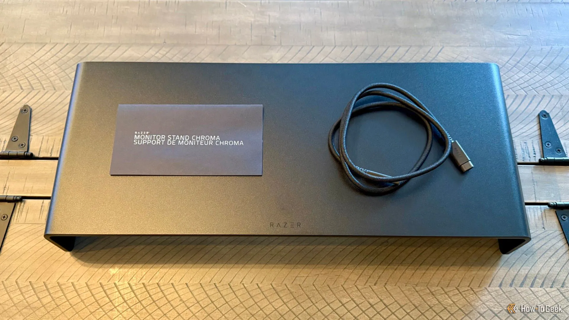Các thành phần trong hộp sản phẩm Razer Monitor Stand Chroma: giá đỡ, cáp USB-C và tài liệu hướng dẫn.