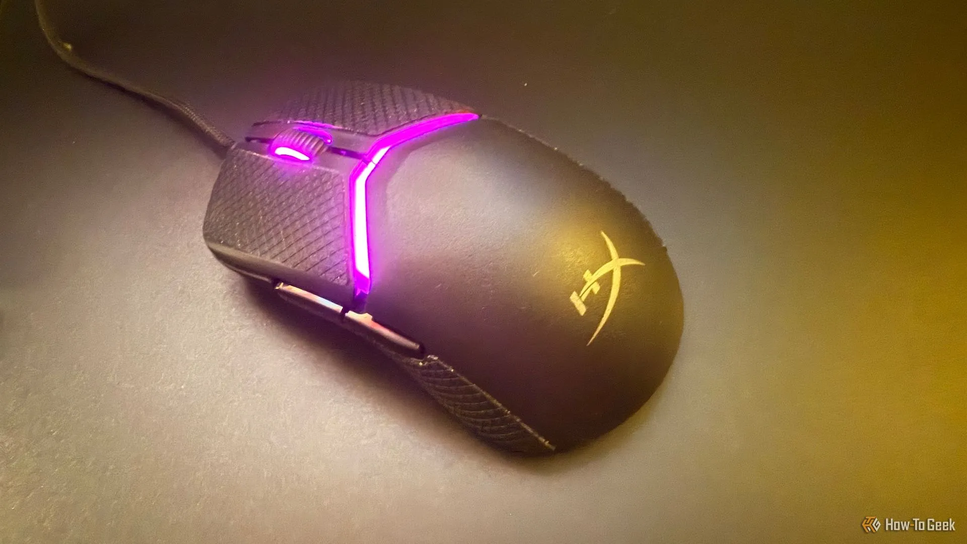 Chuột HyperX Pulsefire Saga trên tấm lót chuột bằng kính, nhìn từ góc trên.