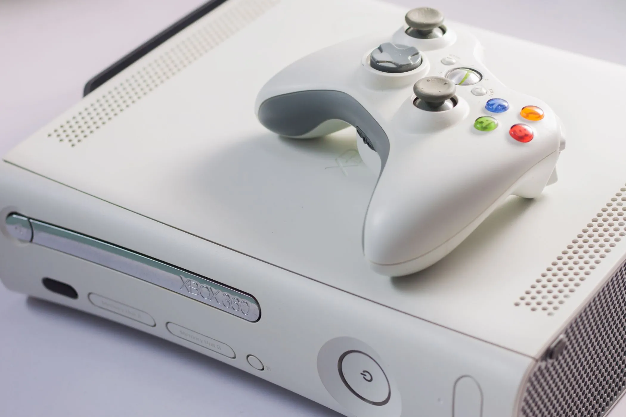 Console Xbox 360 màu trắng cùng tay cầm đặt trên bề mặt