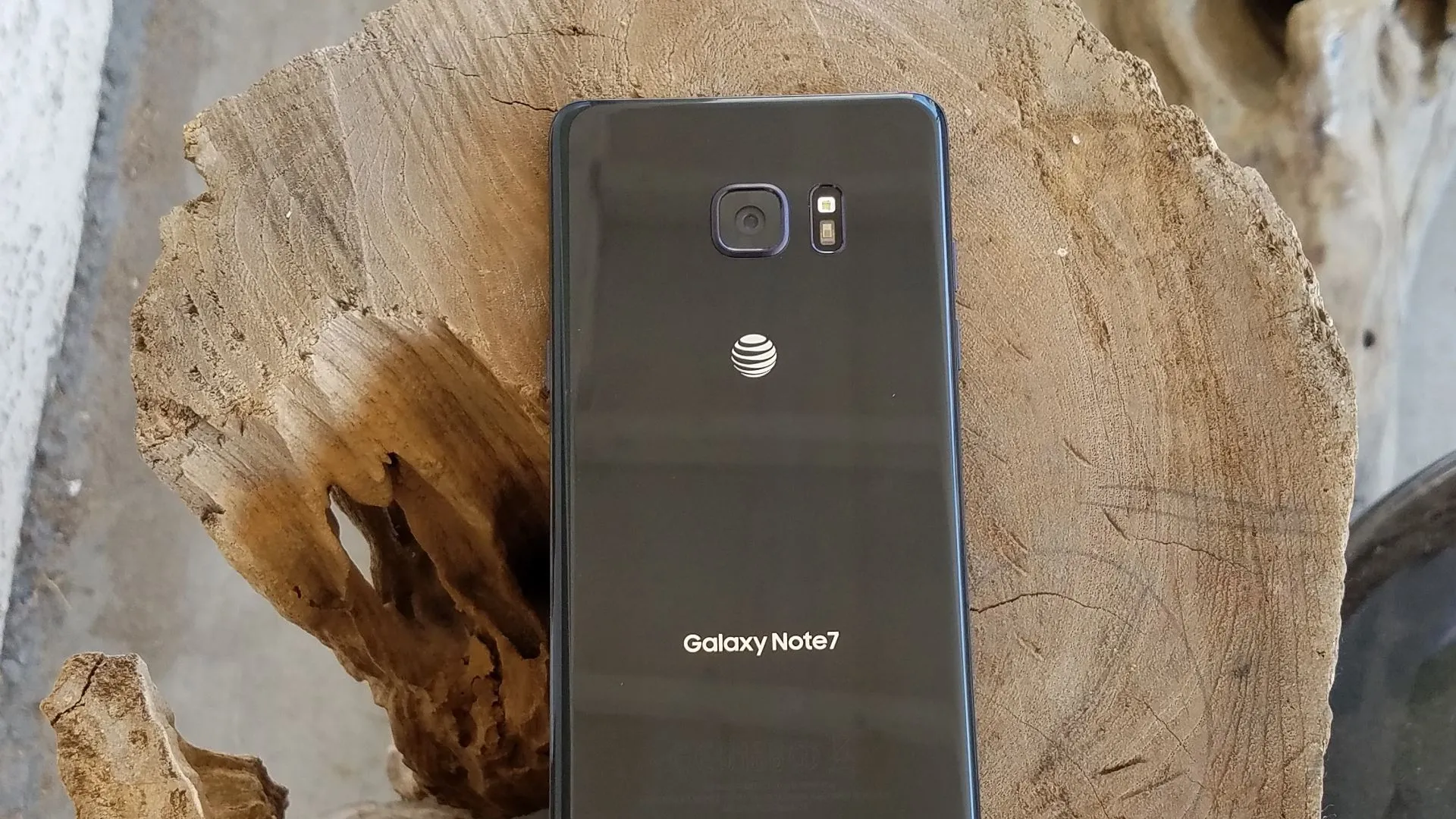 Điện thoại Samsung Galaxy Note 7 màu đen đặt trên khối gỗ, thể hiện thiết kế sang trọng nhưng lại gặp sự cố pin nghiêm trọng.