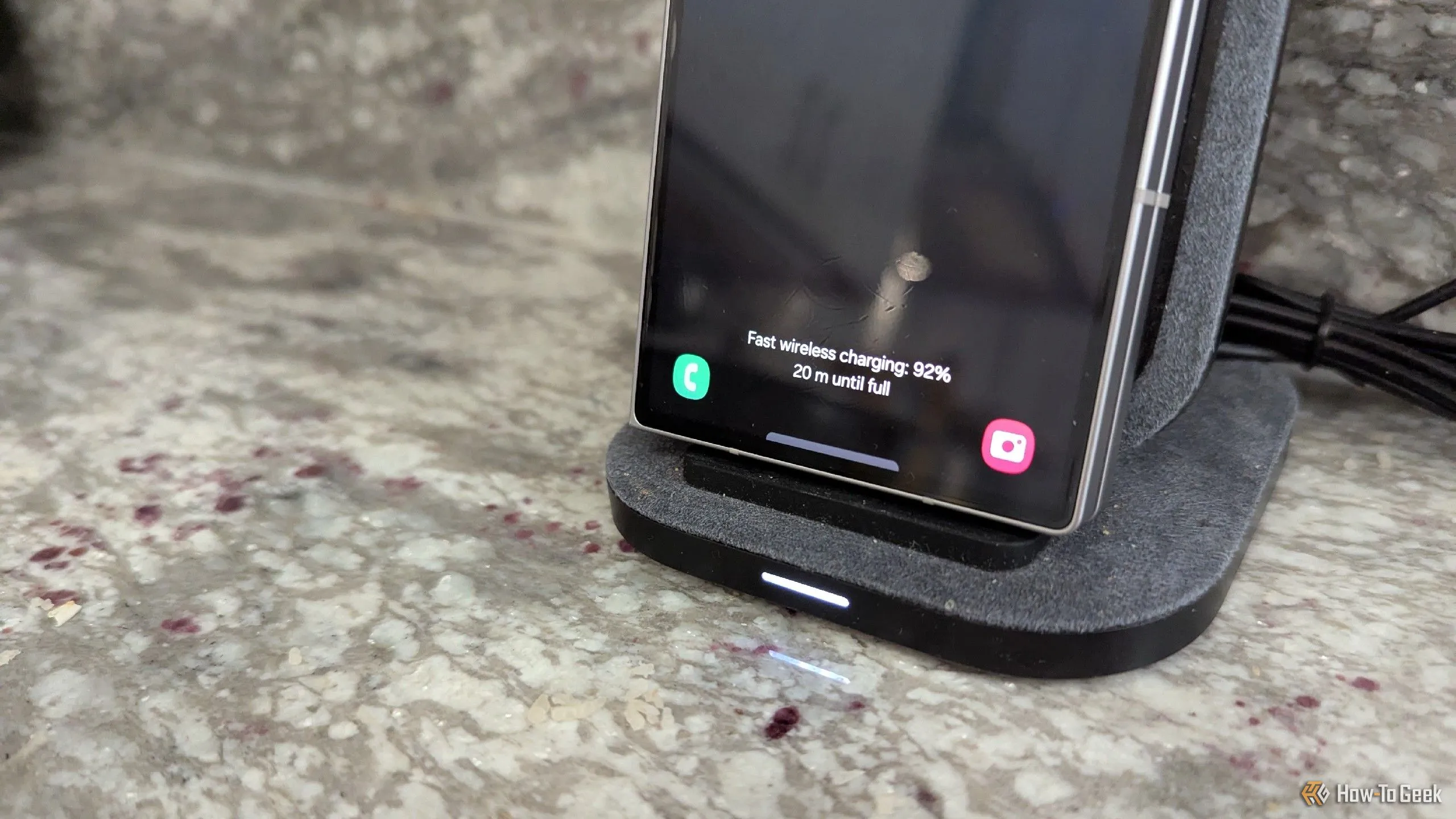 Điện thoại Samsung Galaxy Z Fold 6 gập lại đang đặt trên bộ sạc không dây dạng đứng trong nhà bếp, tiện lợi khi rửa bát.