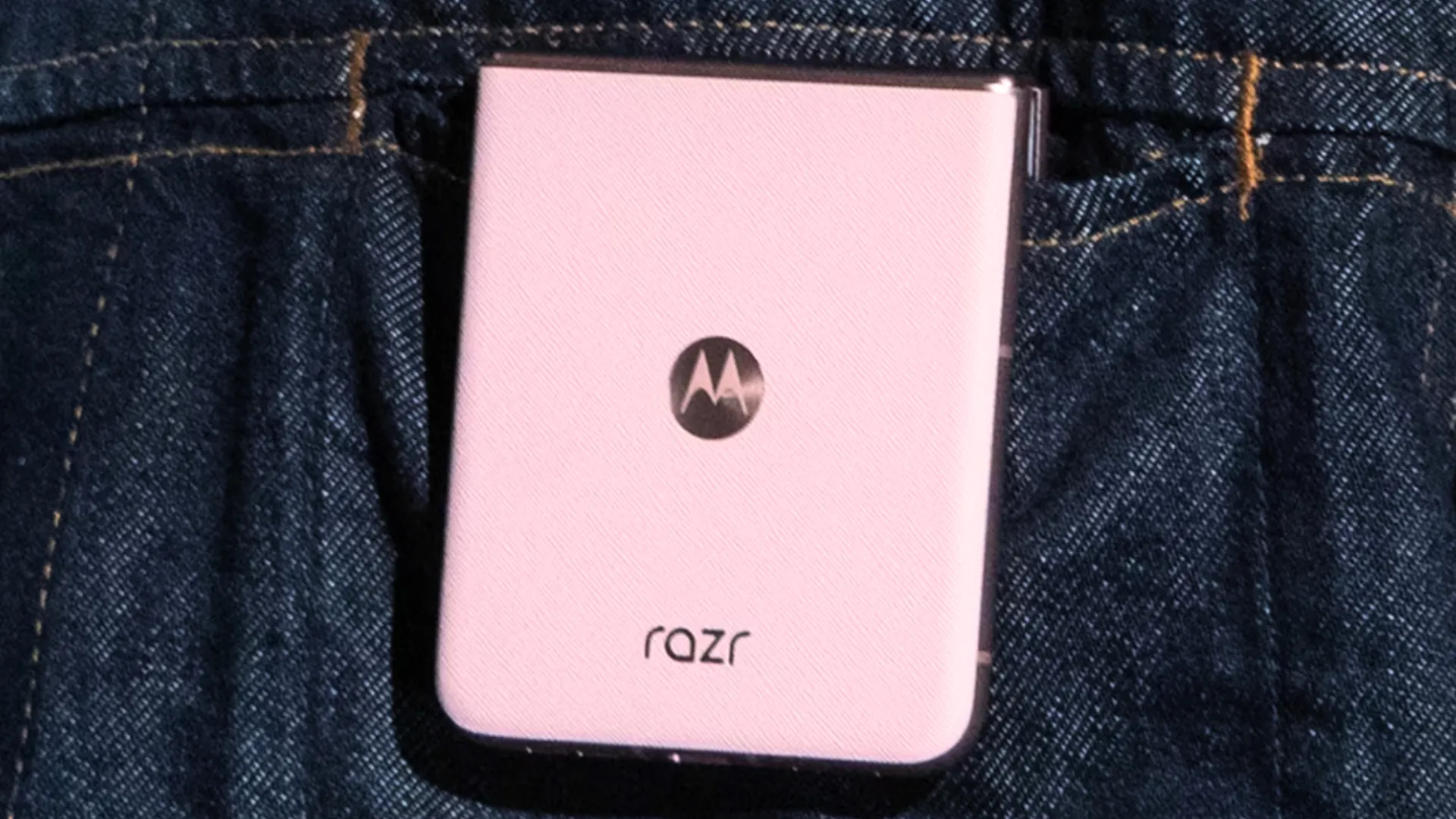 Hình ảnh chiếc điện thoại Motorola Razr 2025 màu hồng nhạt, gập lại và đặt trên bề mặt phẳng, làm nổi bật thiết kế thanh lịch của dòng sản phẩm này.