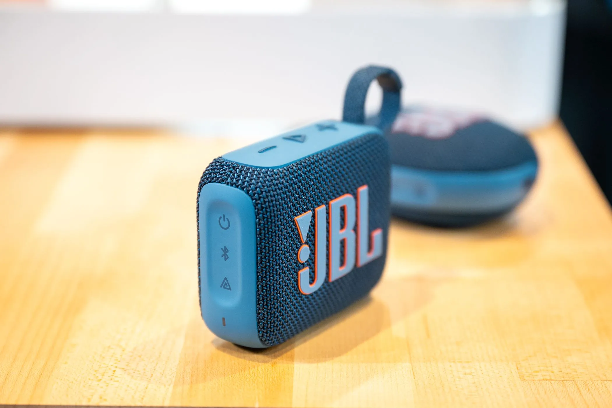 Loa Bluetooth JBL Go 4 đặt trên bàn phía trước JBL Clip 5, thể hiện sự nhỏ gọn và tiện lợi để mang theo