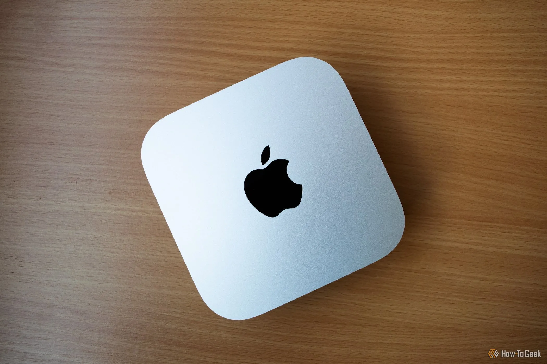 Mac Mini M4 đặt trên bàn gỗ, minh họa khả năng tản nhiệt và vị trí dưới TV cho Mac gaming