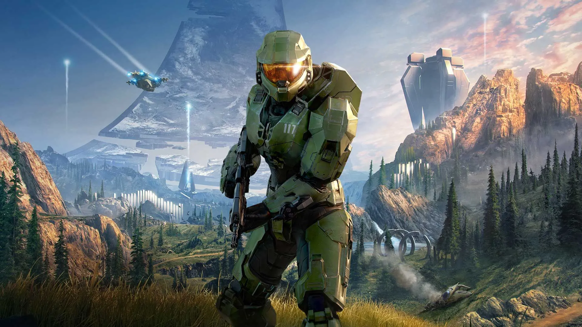 Master Chief trong bộ giáp Spartan cầm vũ khí, đứng trong môi trường cỏ và rừng trên vòng nhẫn Halo Infinite, một game yêu cầu cập nhật lớn dù mua đĩa vật lý.