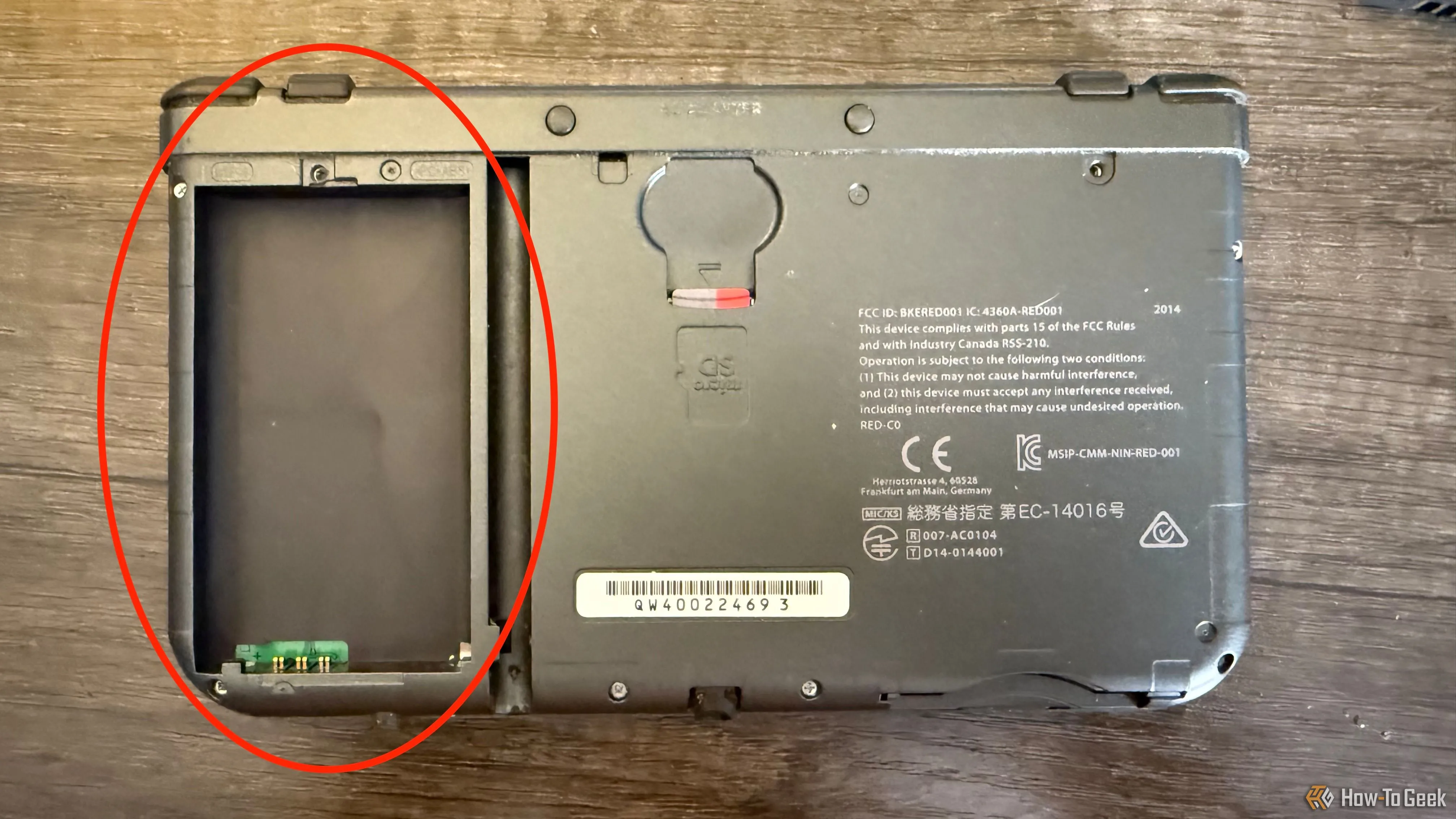 Mặt bên của New Nintendo 3DS XL với khe cắm thẻ nhớ microSD và một vòng tròn quanh khe pin rỗng