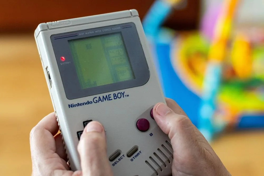 Máy Game Boy (1989) hiển thị game Tetris, minh họa game giải đố thời gian thực phù hợp với điều khiển D-pad.