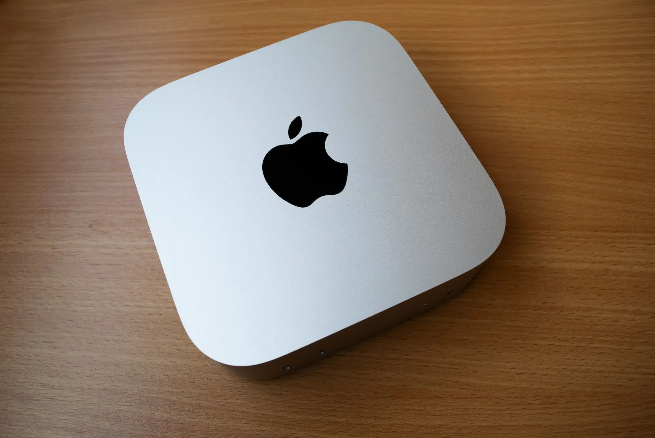 Máy tính Apple M4 Mac Mini nhỏ gọn màu bạc đặt trên bàn gỗ, tượng trưng cho sức mạnh xử lý ổn định và hiệu quả năng lượng cho công việc hàng ngày.