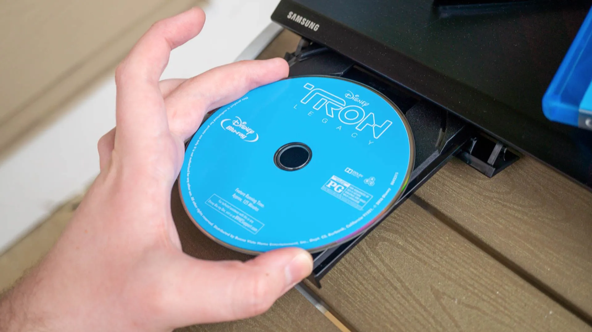 Một đĩa Blu-ray đặt cạnh đầu phát Blu-ray, minh họa khả năng xem nội dung giải trí qua đĩa vật lý trên console