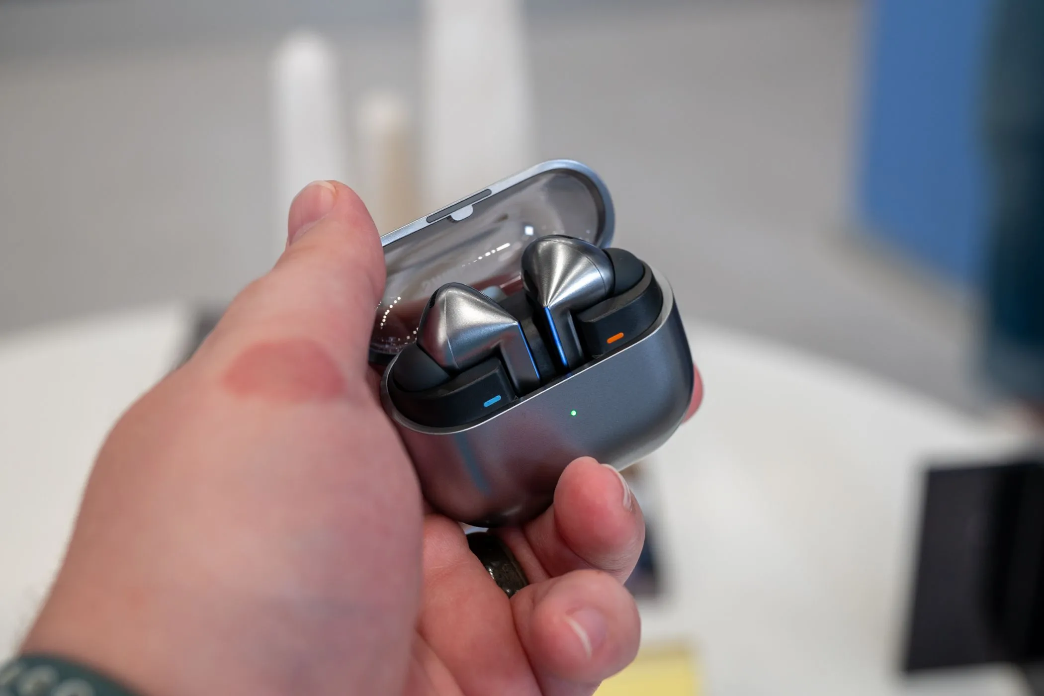 Một người đang cầm hộp sạc mở của Samsung Galaxy Buds 3 Pro, cho thấy thiết kế tai nghe và hộp sạc trong suốt, nhấn mạnh sự tiện lợi.