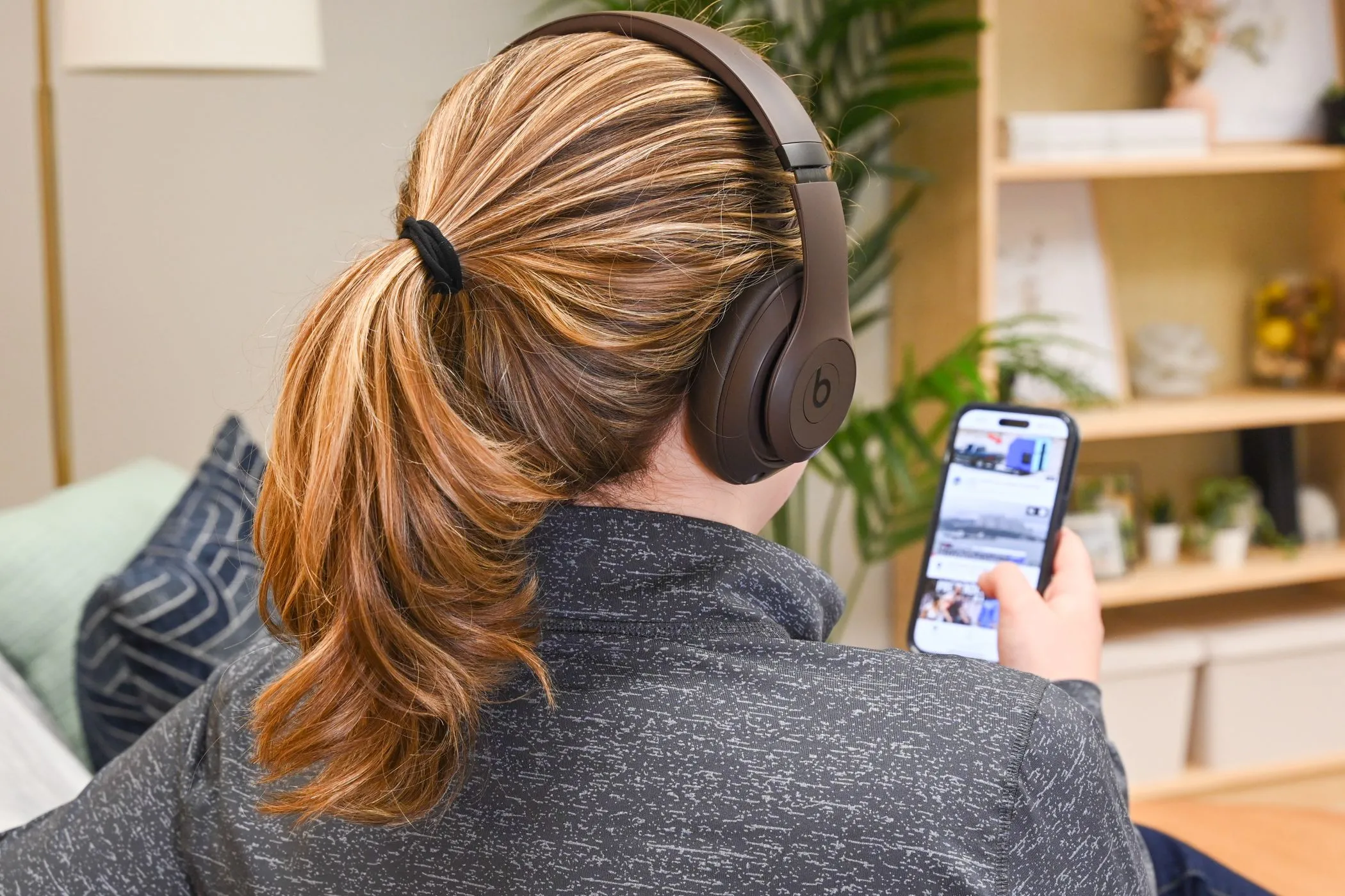 Một người dùng xem video trên iPhone với tai nghe, thể hiện cách chúng ta tiêu thụ nội dung và sản phẩm được đề xuất bởi influencer, kể cả AI.