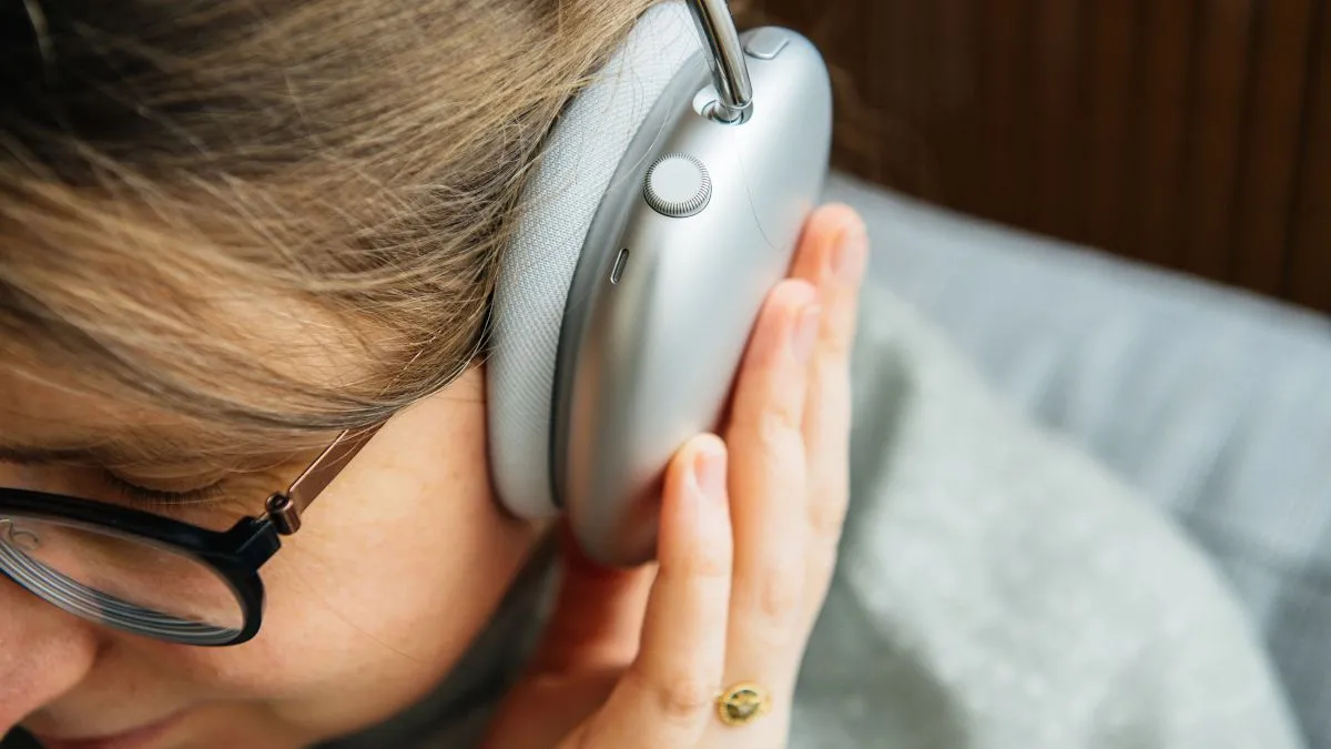 Một người phụ nữ đeo tai nghe over-ear, tượng trưng cho trải nghiệm âm thanh cá nhân và tính năng xuyên âm của tai nghe hiện đại.
