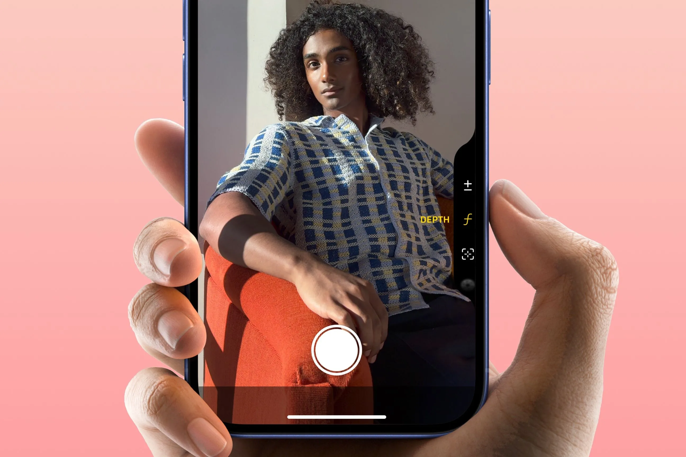 Ngón trỏ nhấn vào nút Camera Control của iPhone 16, hiển thị màn hình ứng dụng camera sẵn sàng chụp.