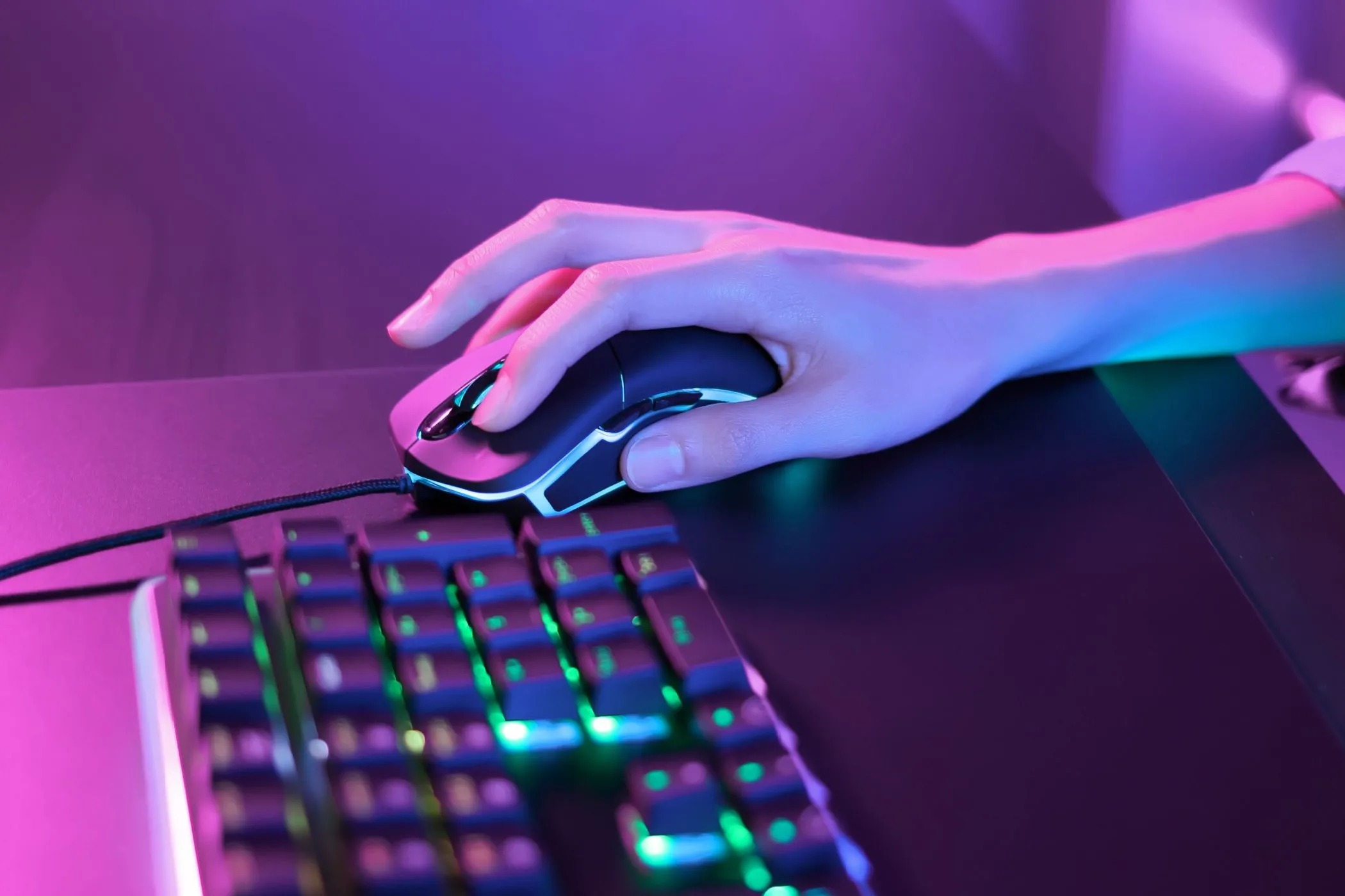 Người chơi đang sử dụng chuột gaming trong không gian ánh sáng neon hồng, thể hiện sự thư giãn và tập trung.