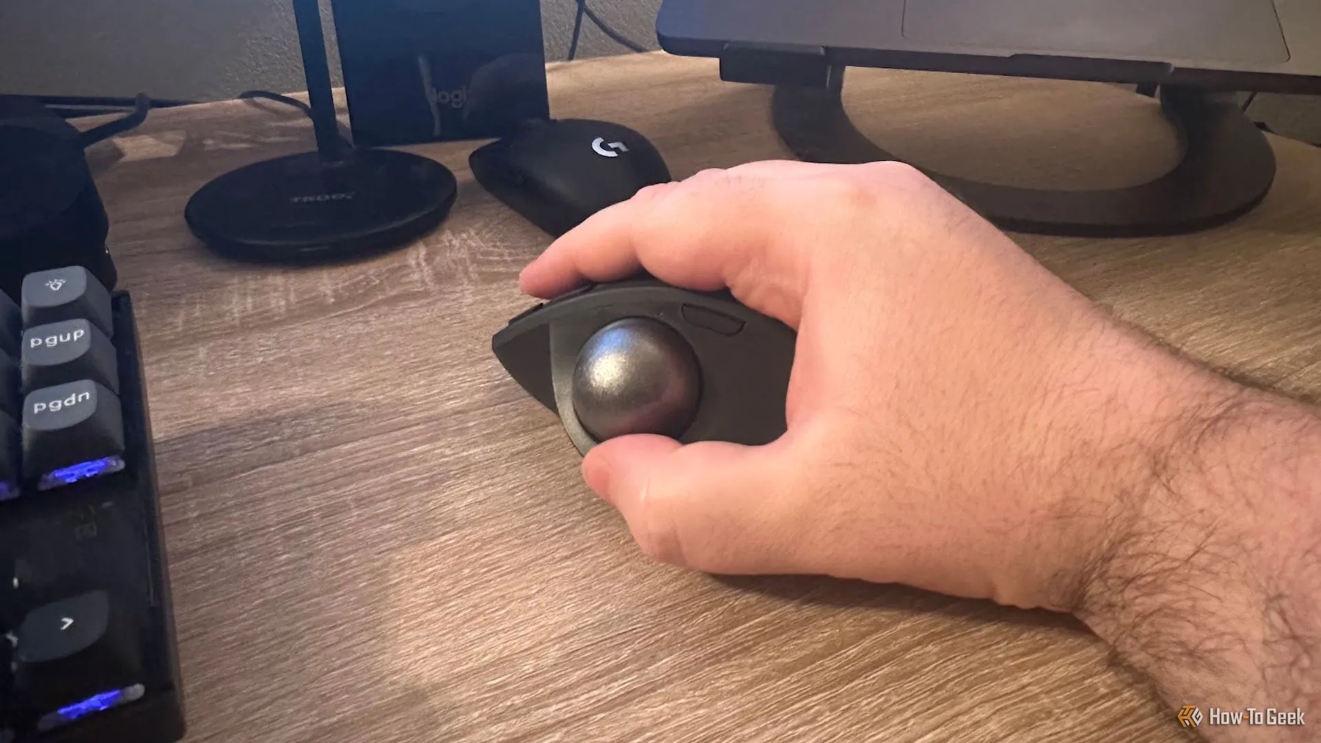 Người dùng cầm chuột Logitech MX Ergo S, minh họa thiết kế công thái học giúp giảm căng thẳng cổ tay khi sử dụng.