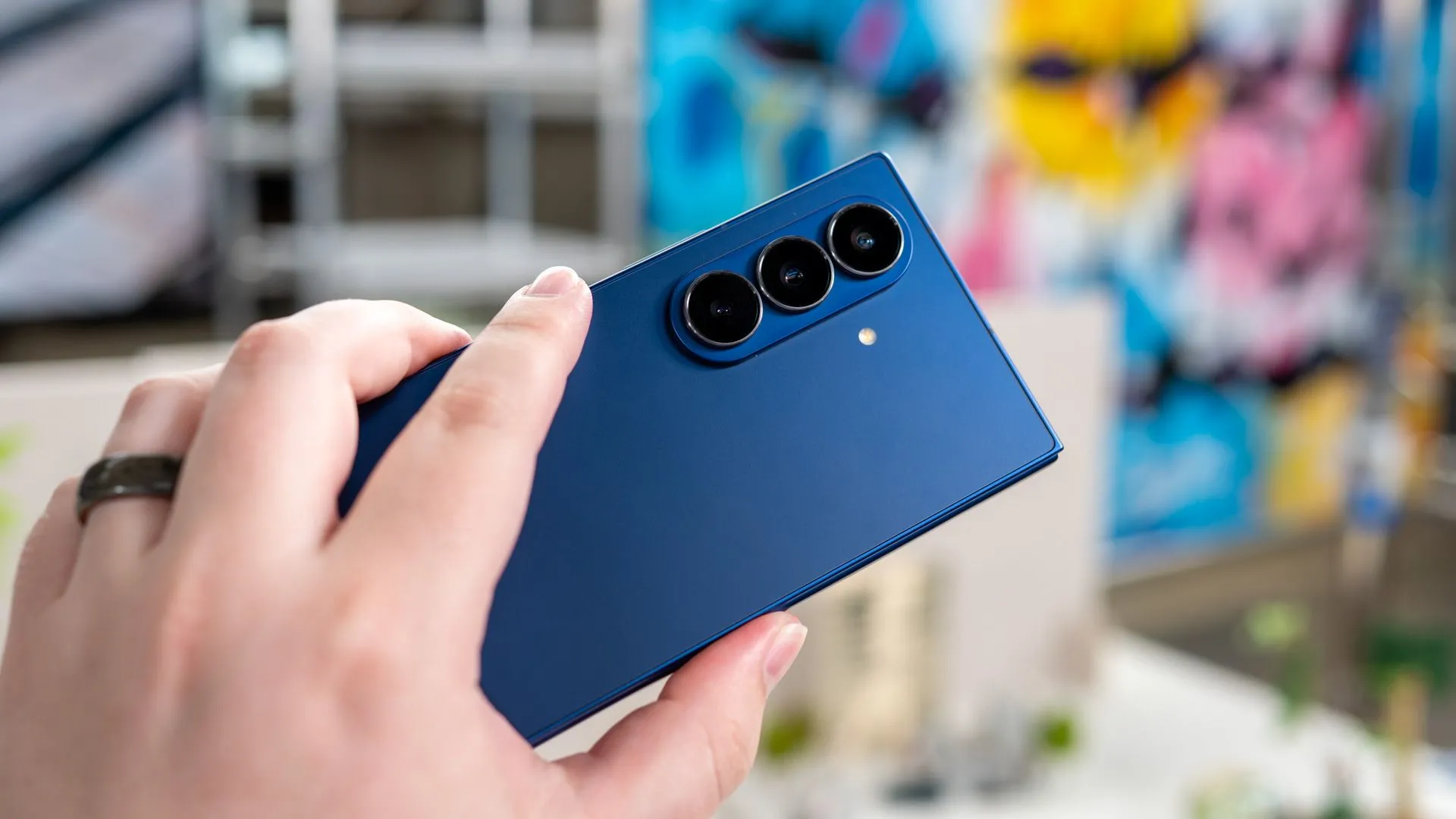Người dùng đang cầm điện thoại Samsung Galaxy Z Fold 7 mở ra, cho thấy thiết kế mặt lưng và cụm camera sau 200MP được nâng cấp.