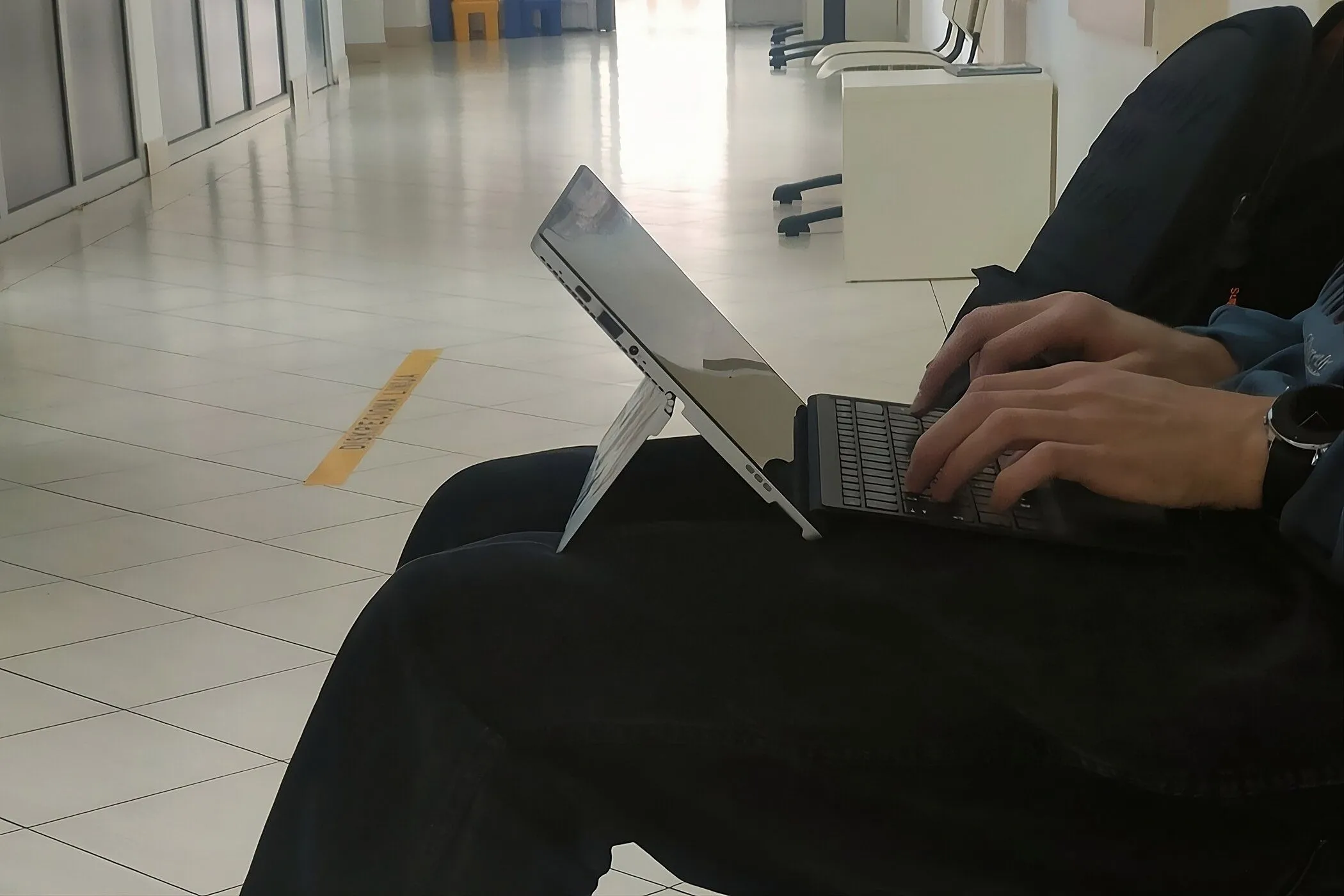 Người dùng đang gõ phím trên laptop 2-in-1 đặt trên đùi, minh họa cách sử dụng thiết bị di động