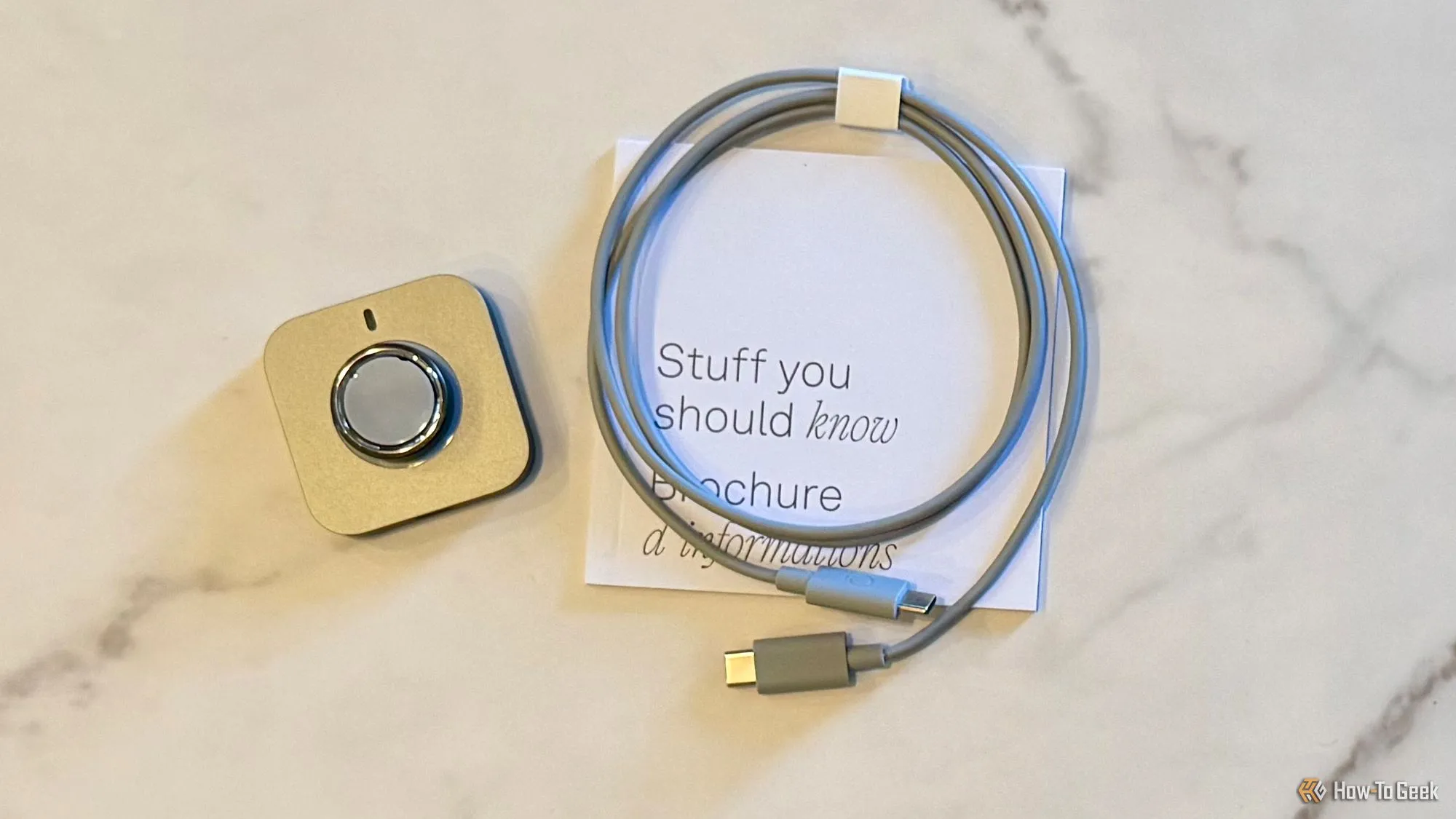 Nội dung hộp Oura Ring 4 gồm nhẫn, đế sạc và cáp USB-C, thể hiện sự tối giản và tiện lợi
