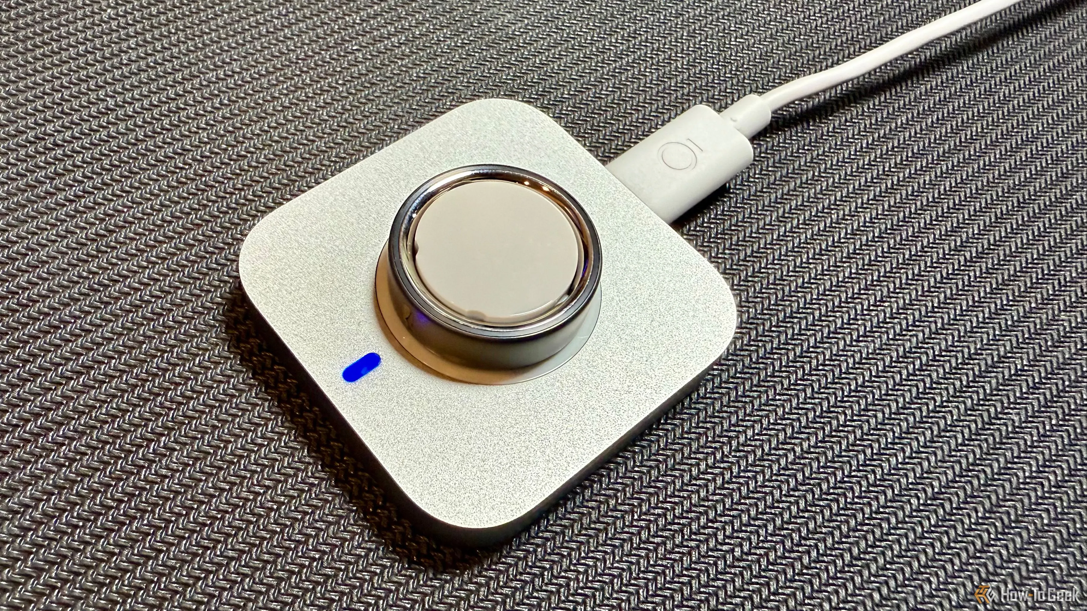 Oura Ring 4 đang được sạc trên đế sạc không dây nhỏ gọn, cho thấy quá trình sạc tiện lợi và nhanh chóng
