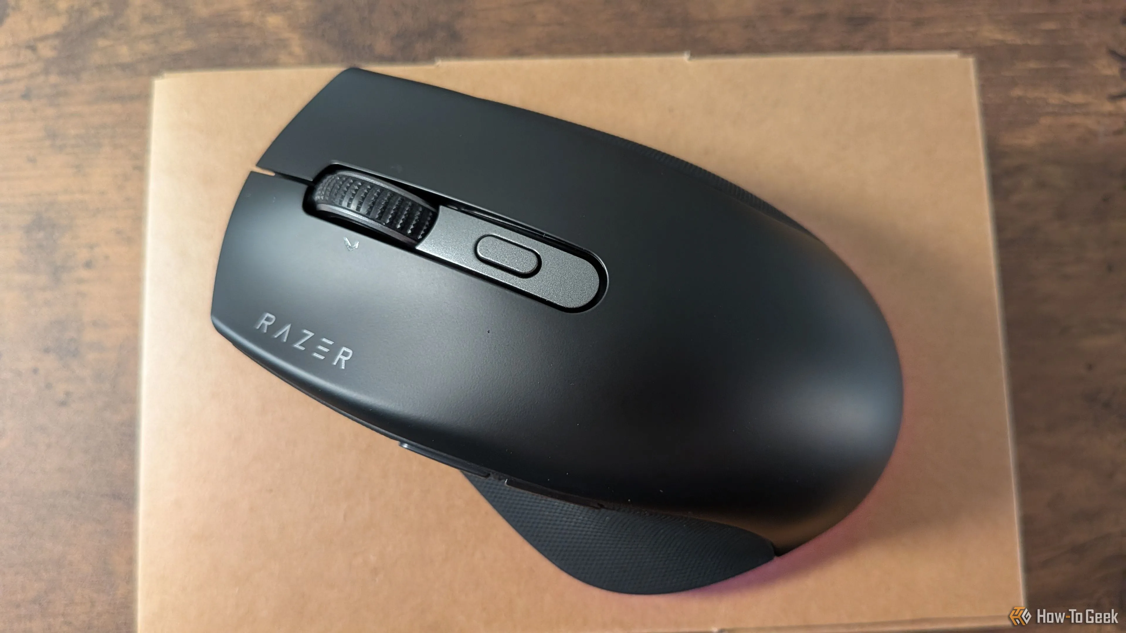 Razer Pro Click V2 on top of its box with its LED lights on.