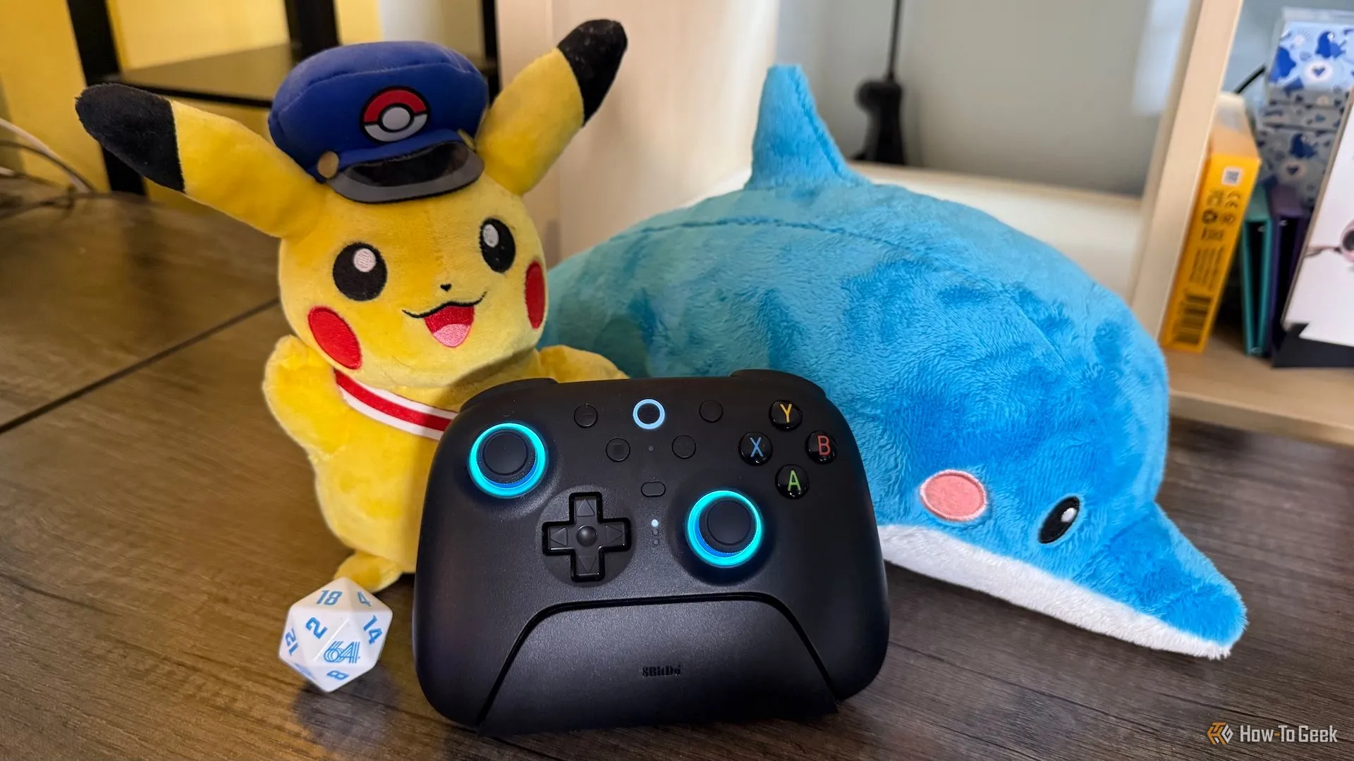 Tay cầm chơi game 8BitDo Ultimate 2 Wireless trên dock sạc, cùng các phụ kiện gaming trang trí.