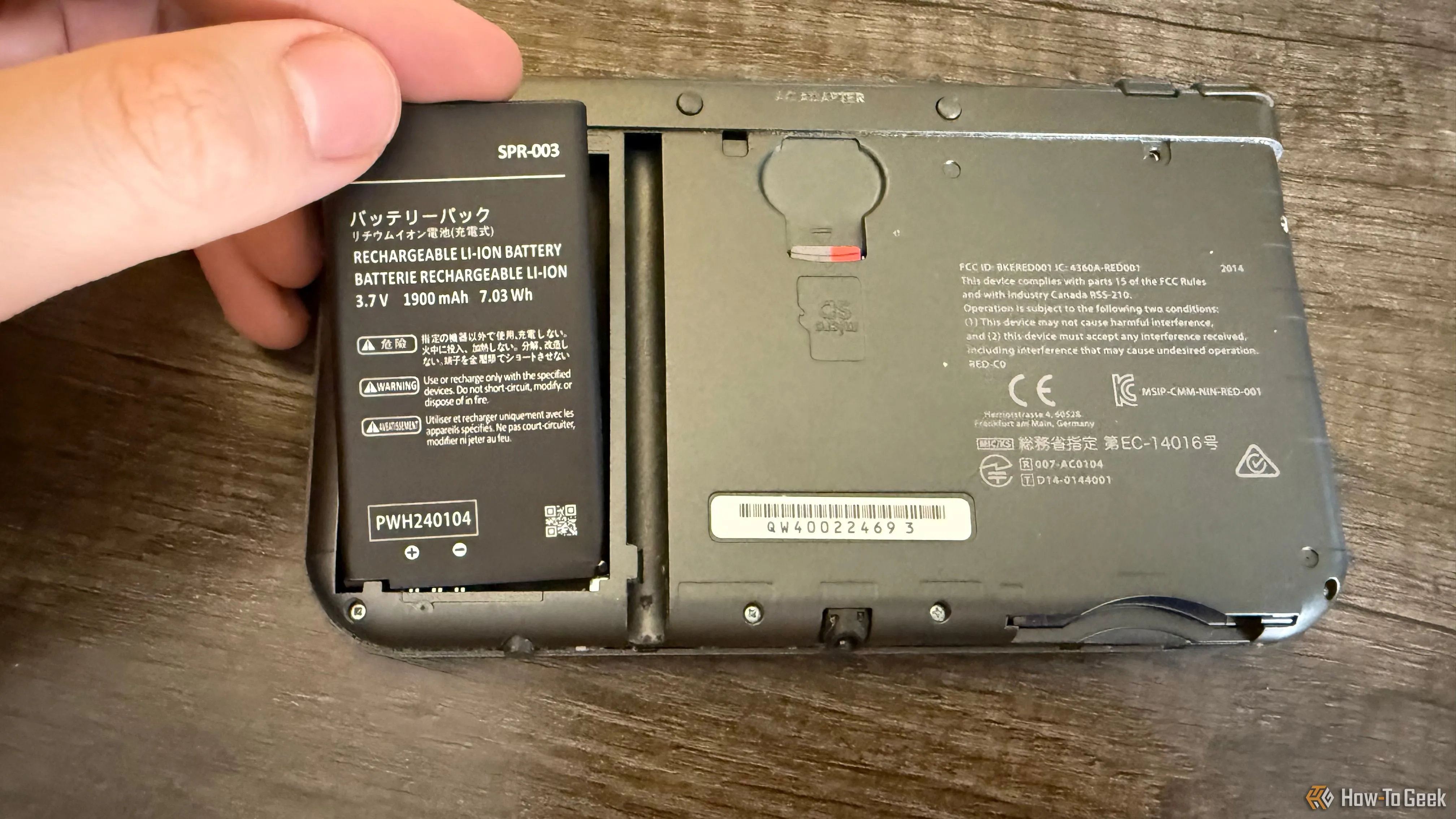 Tay đang đặt một viên pin vào New Nintendo 3DS XL